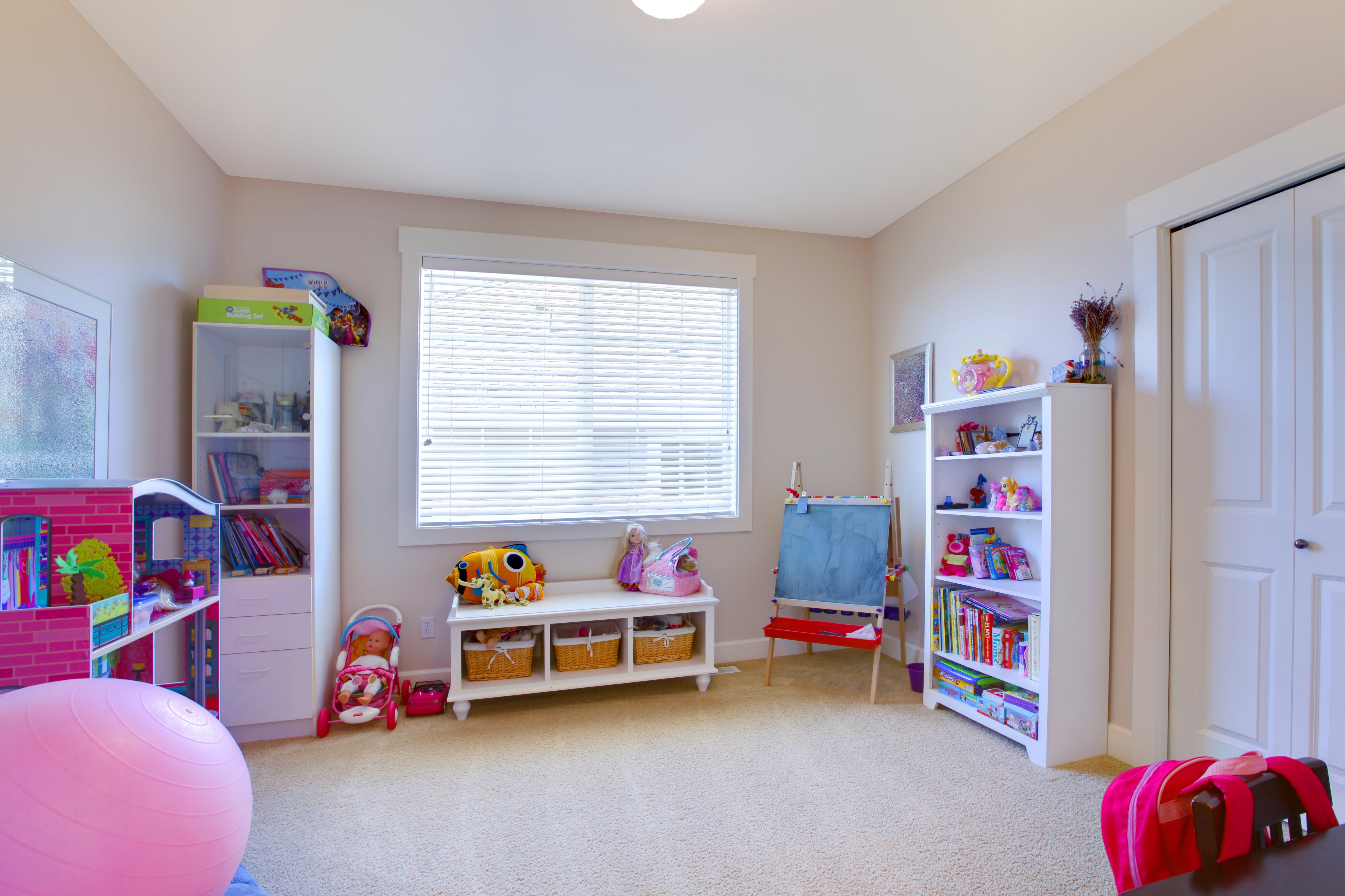 A neatly organized playroom with multiple white shelving units