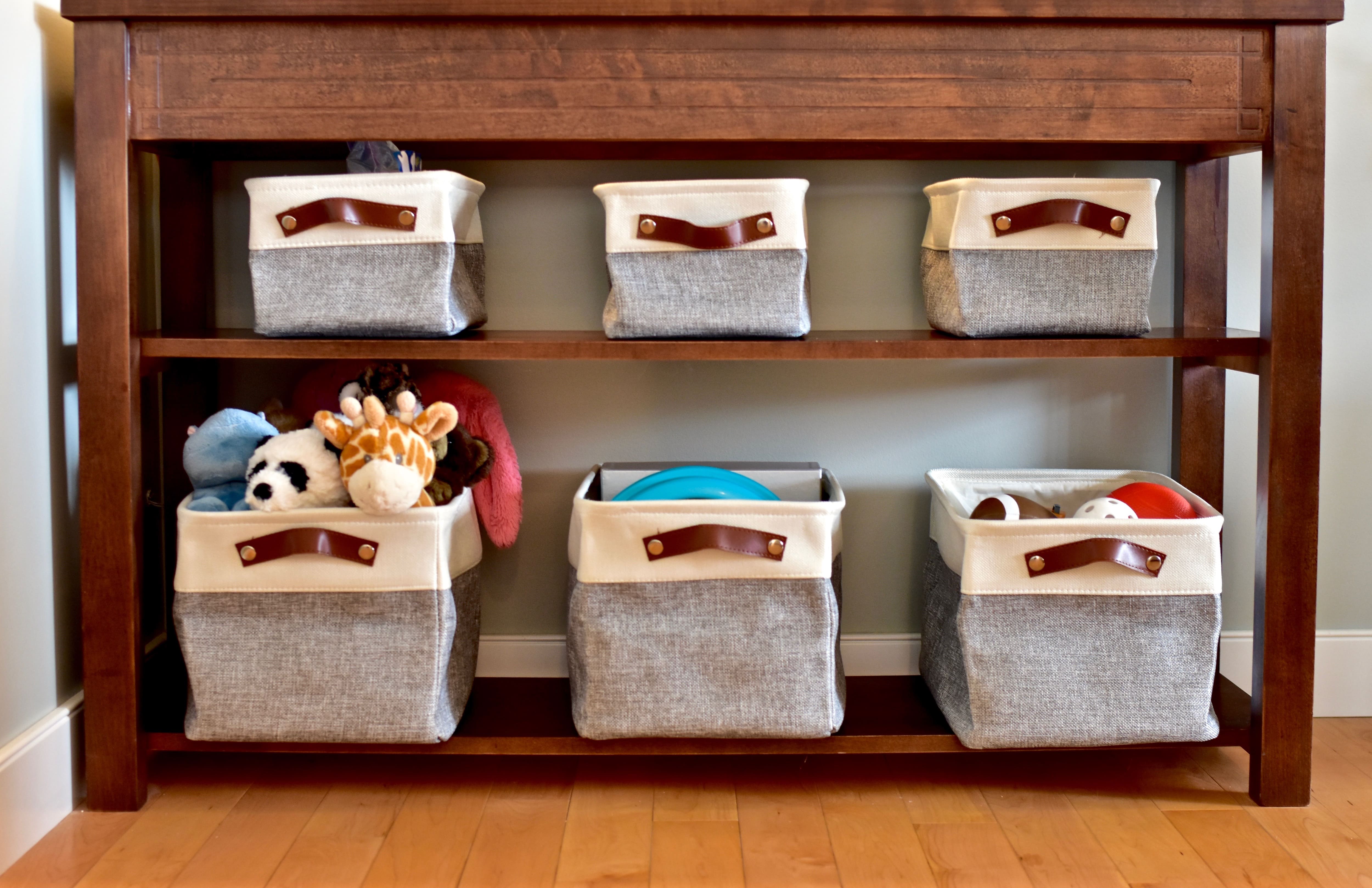 A tall wood accent table with six canvas storage baskets filled with toys