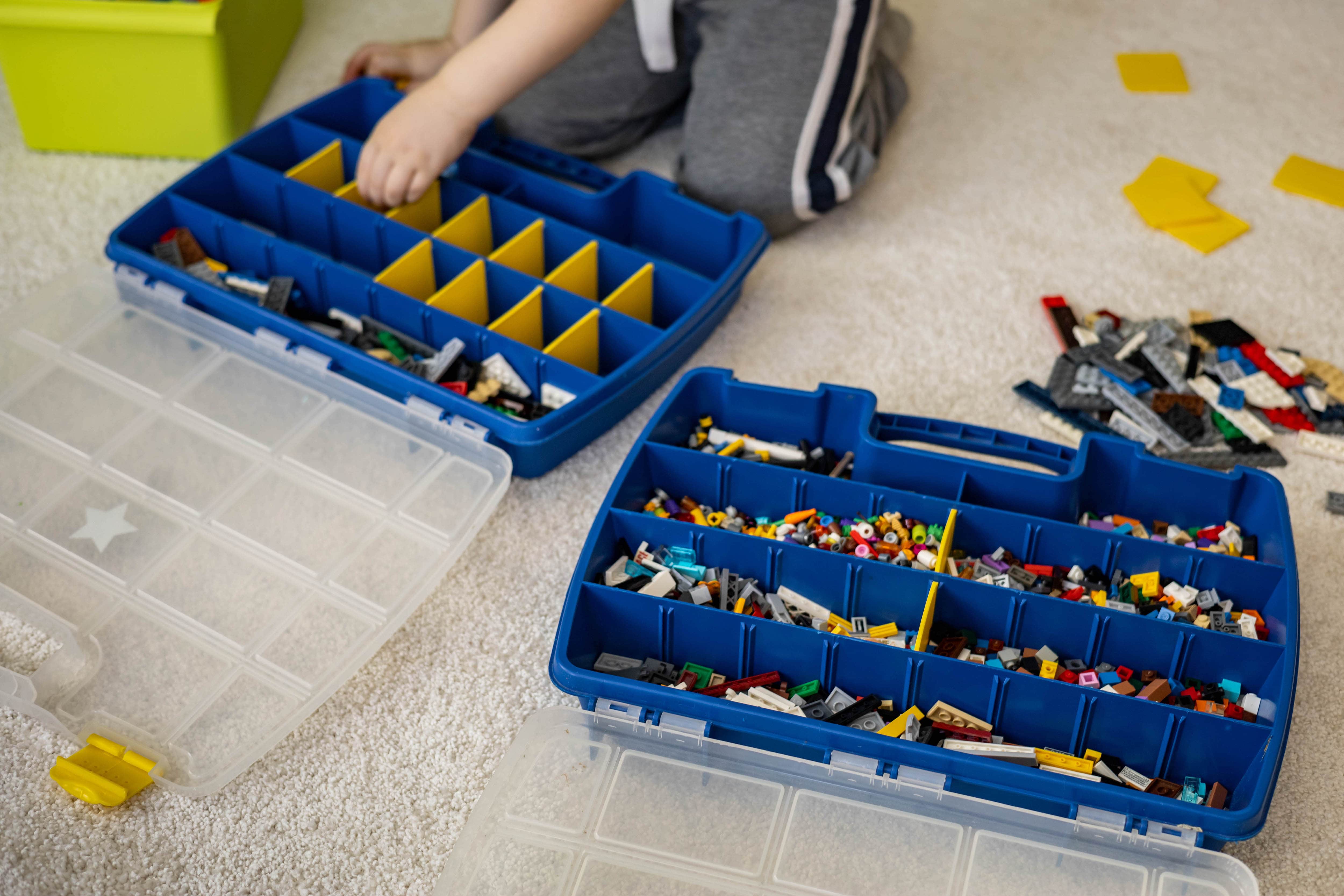 A young kid organizing Lego blocks in compartment organizers