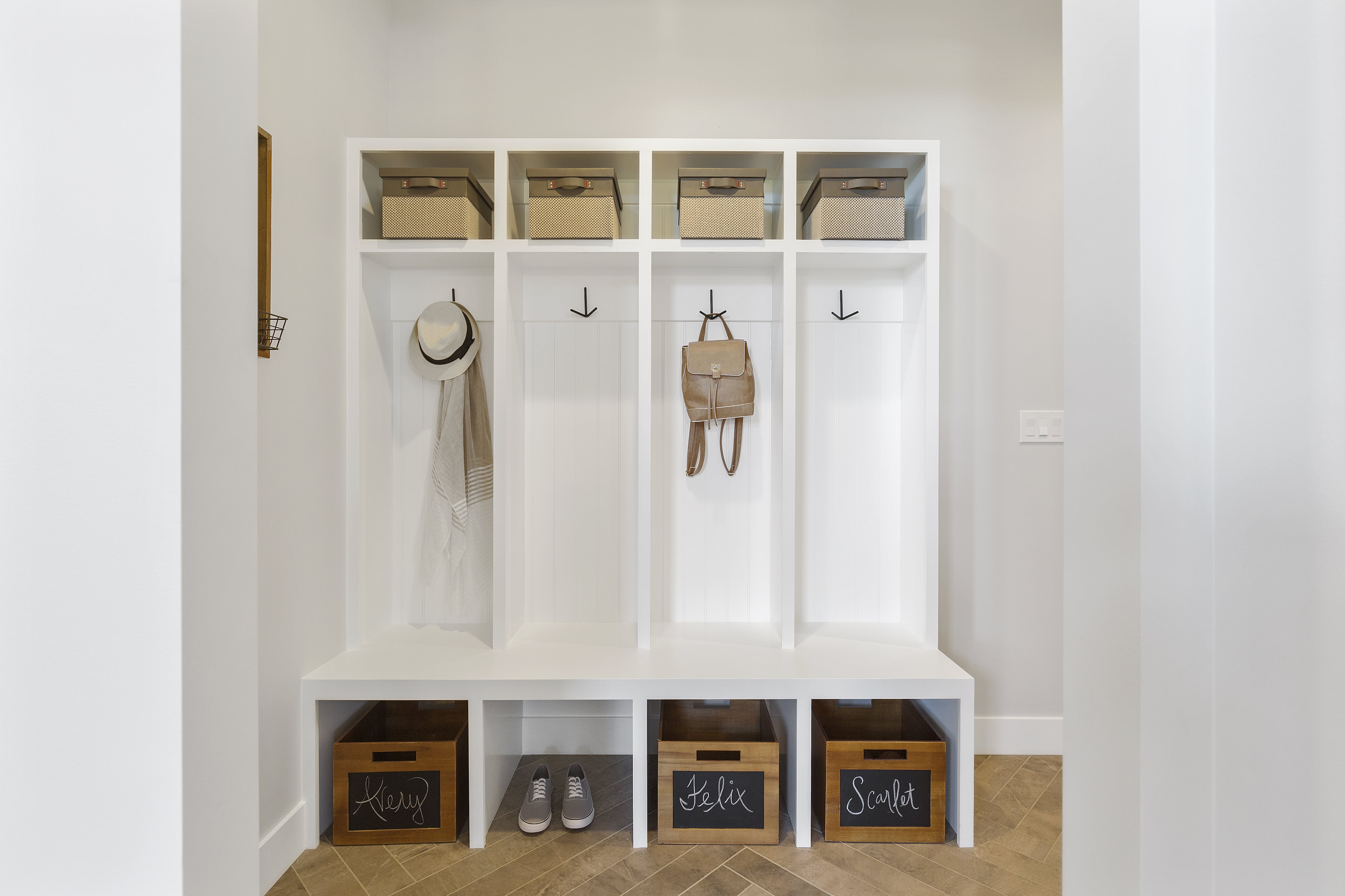 A clean white hallway with a mud bench and cubbies for storage