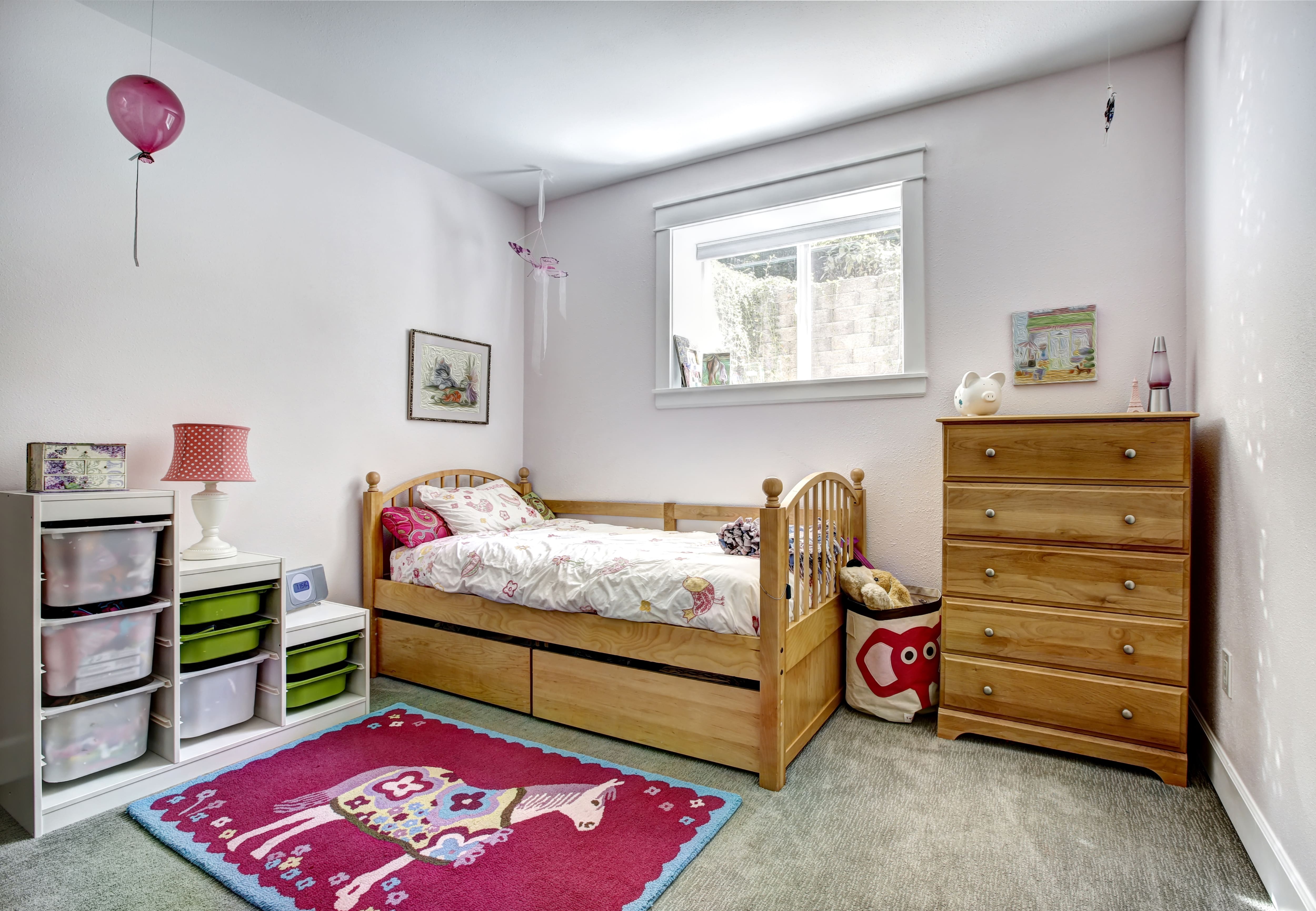 A young girl’s room with a wooden daybed and a matching dresser