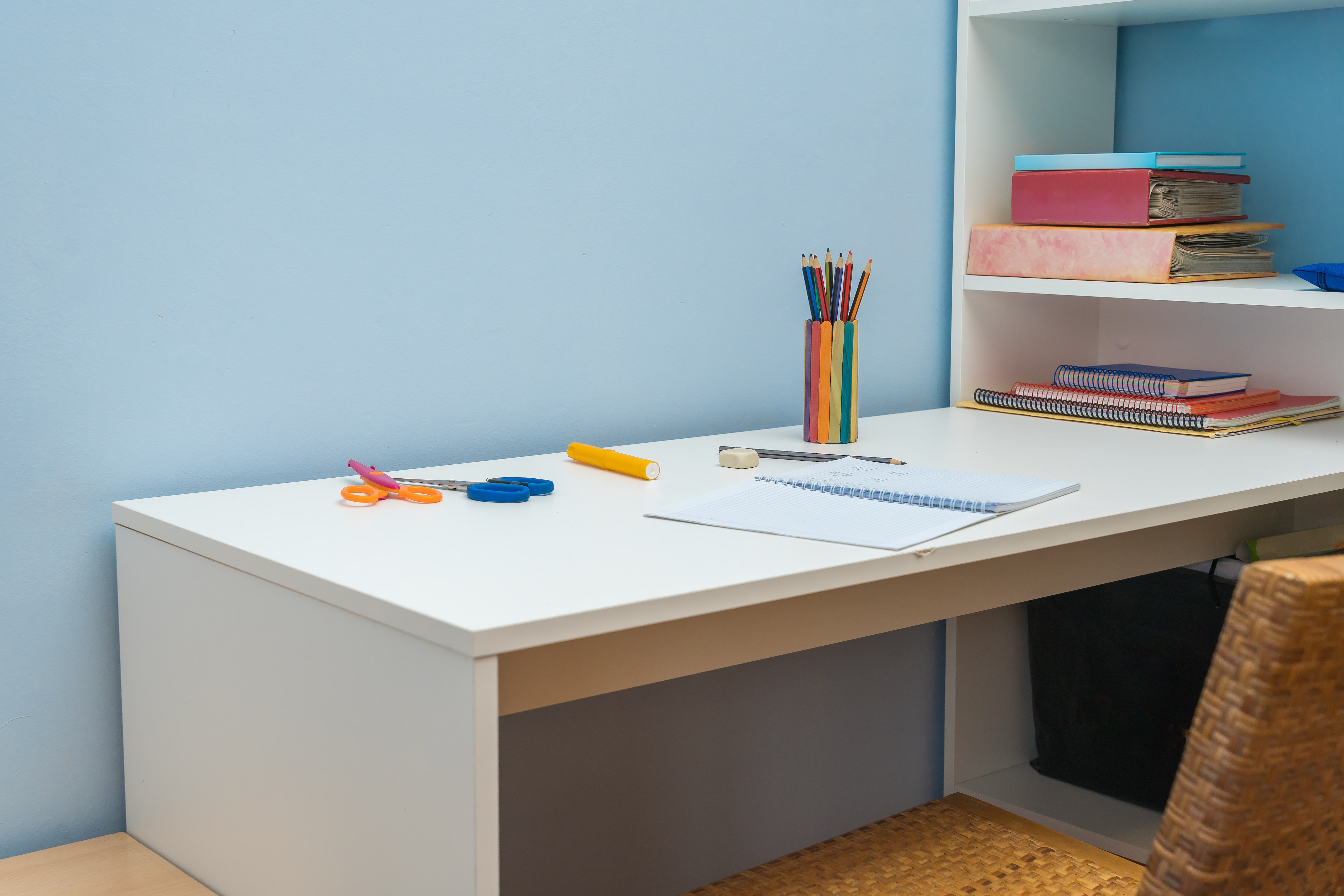 A white desk attached to a bookshelf in a kid’s room