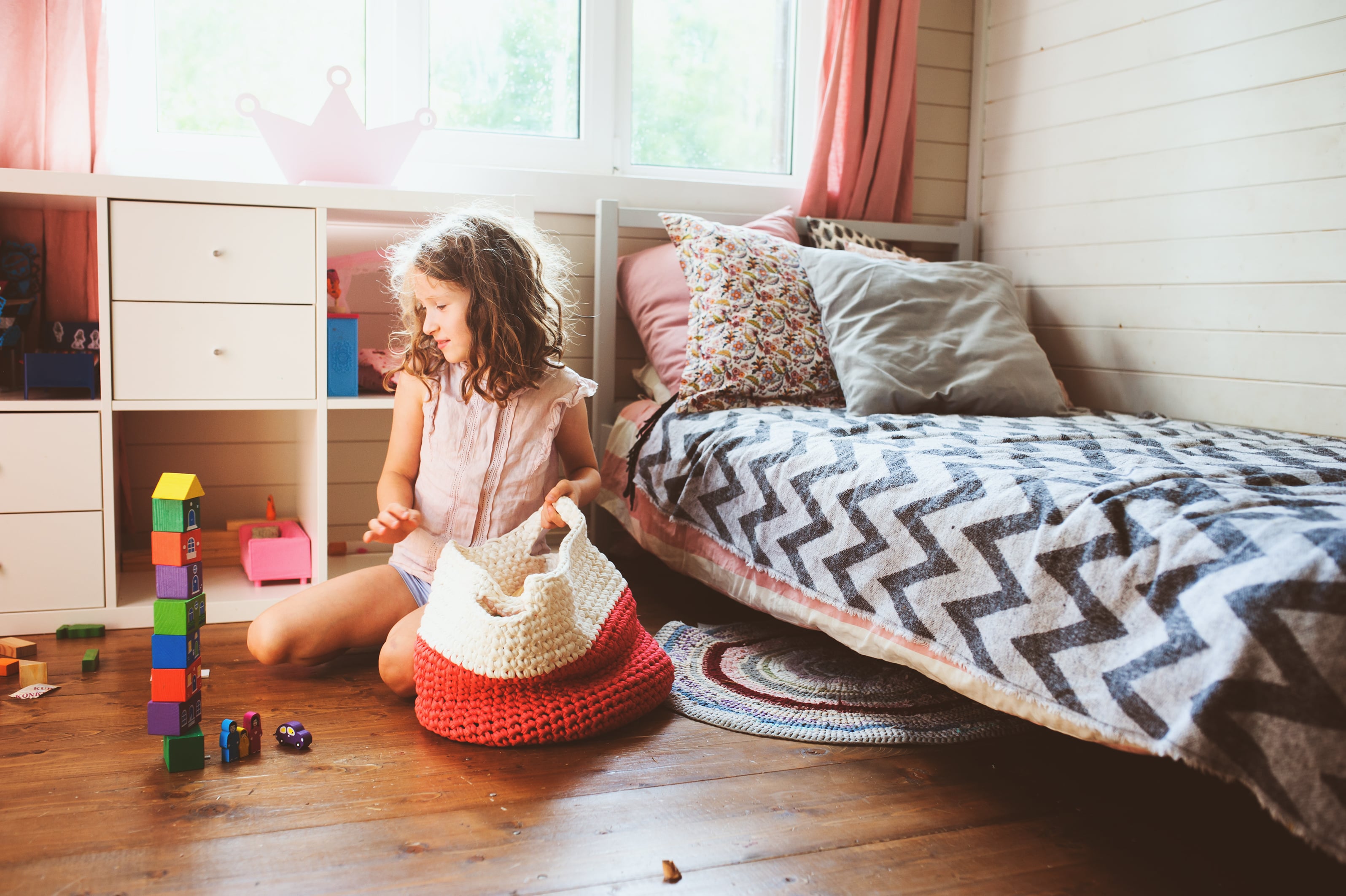 A young girl taking wooden blocks out of a knitted tote bag