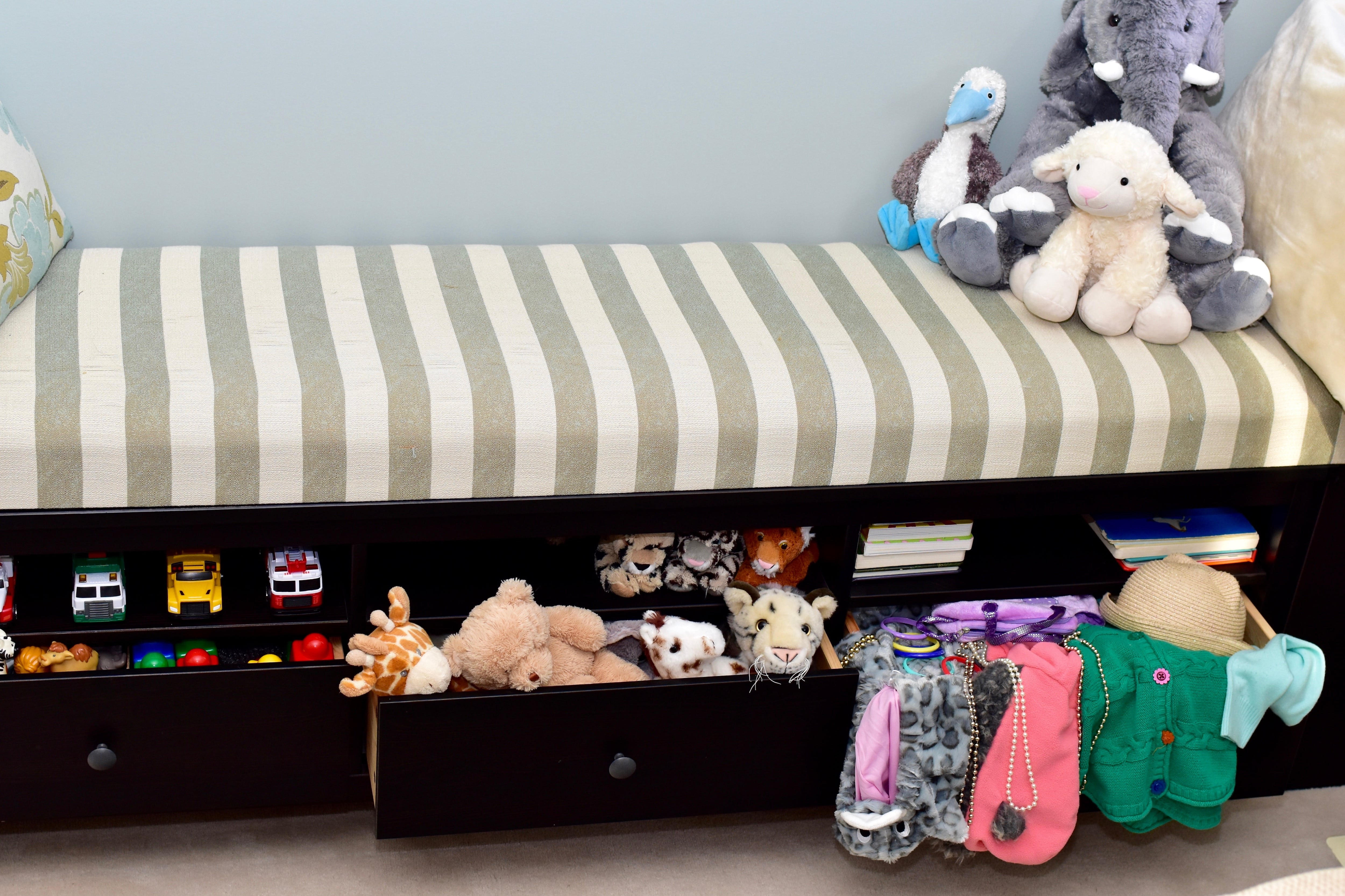 A striped upholstered bench with drawers for storage underneath