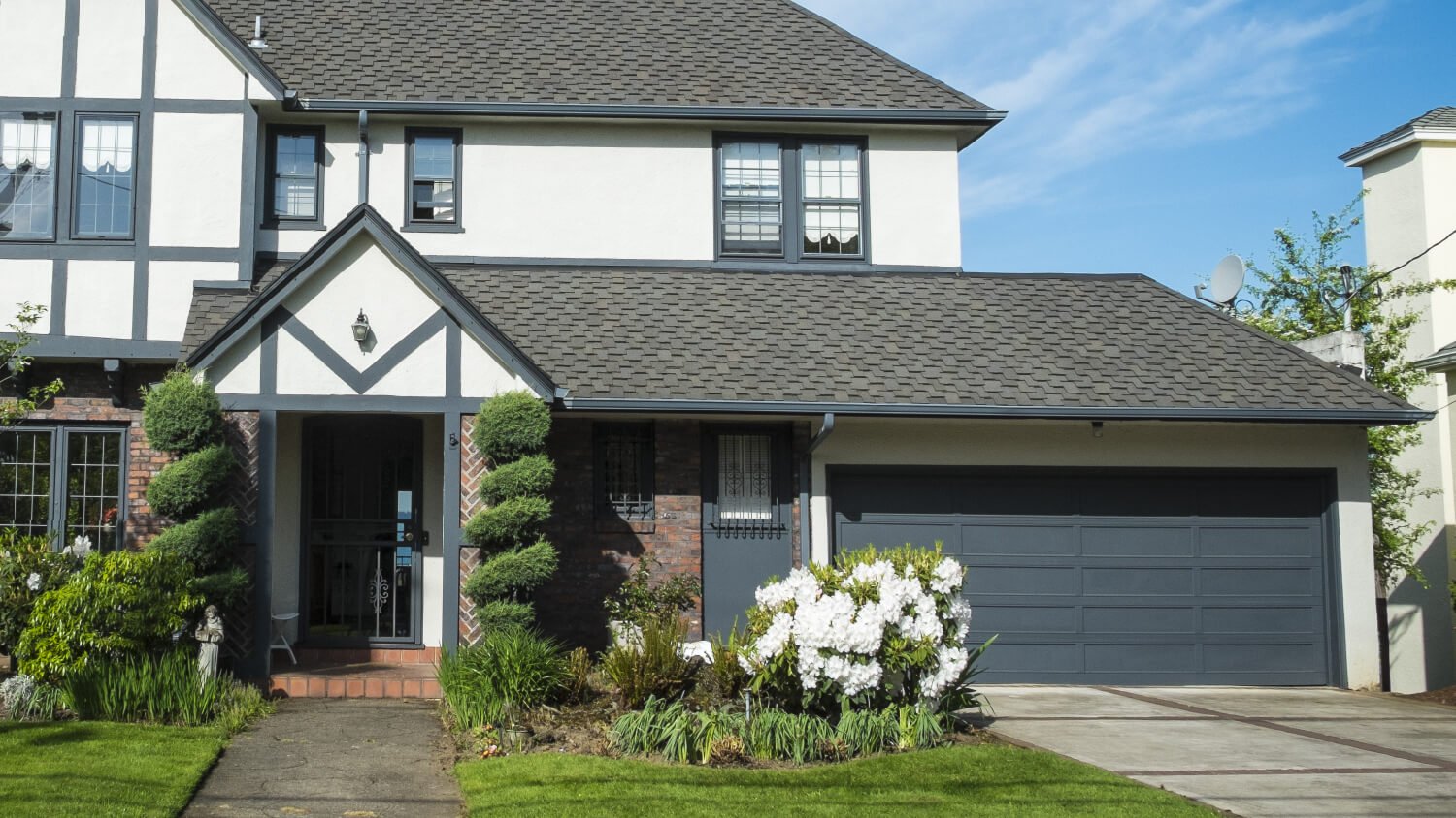 tudor style house with matching garage door and landscaping