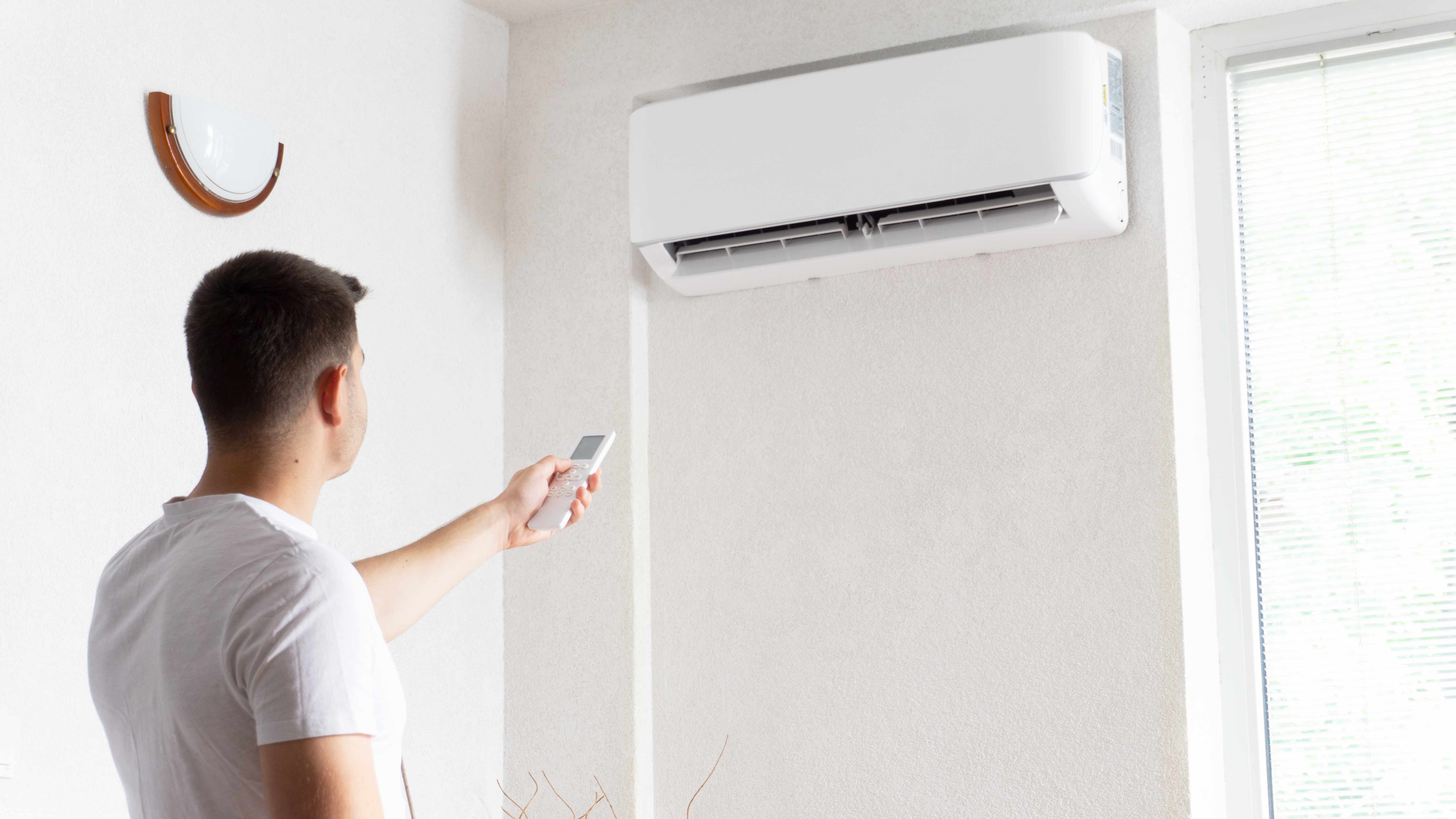 Man using remote to turn mini-split AC on 