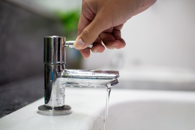 Man turning off sink faucet