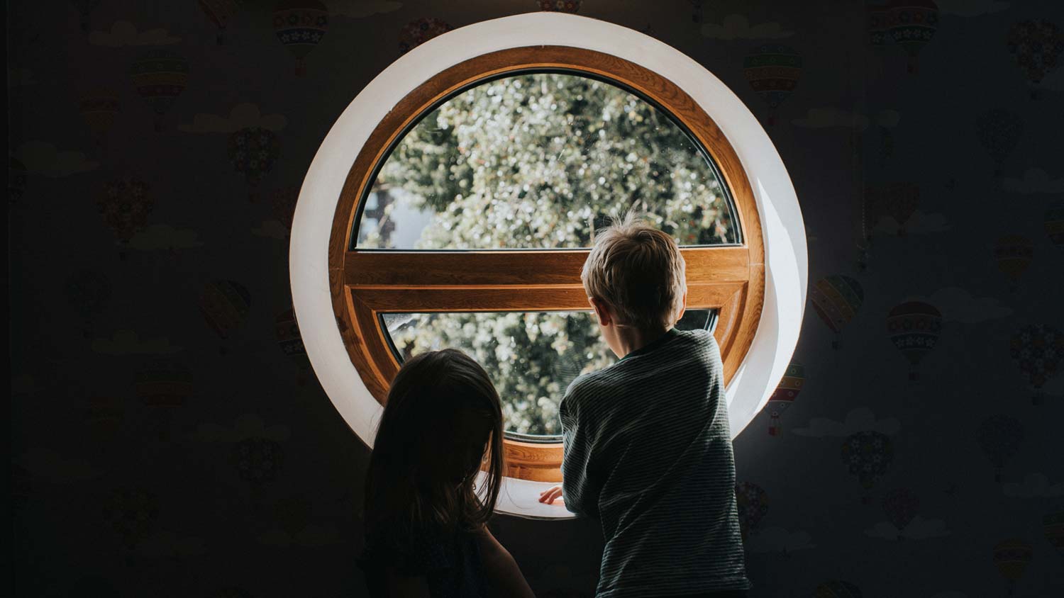 Two children looking out a circular window