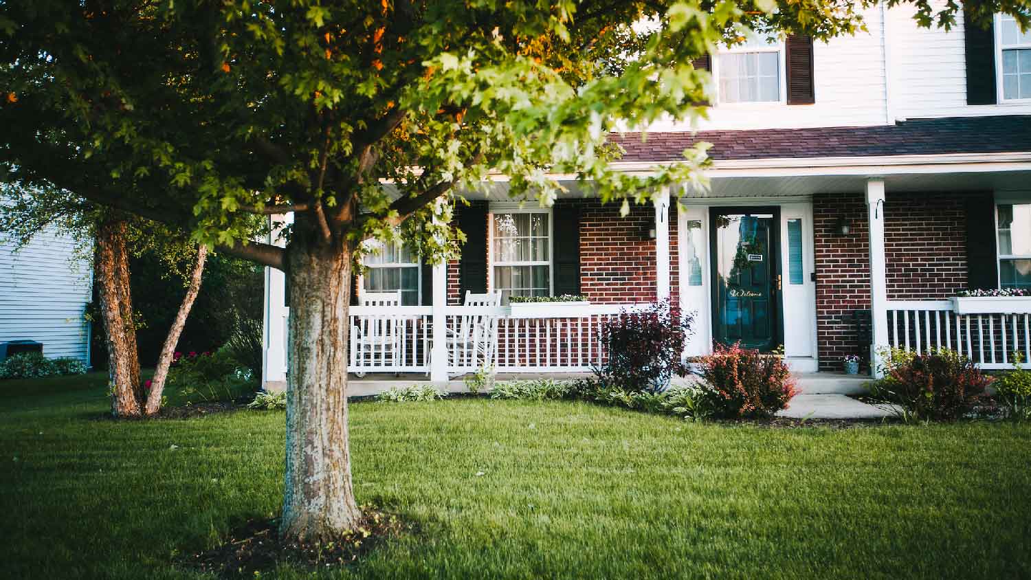 A two-story house with a large tree