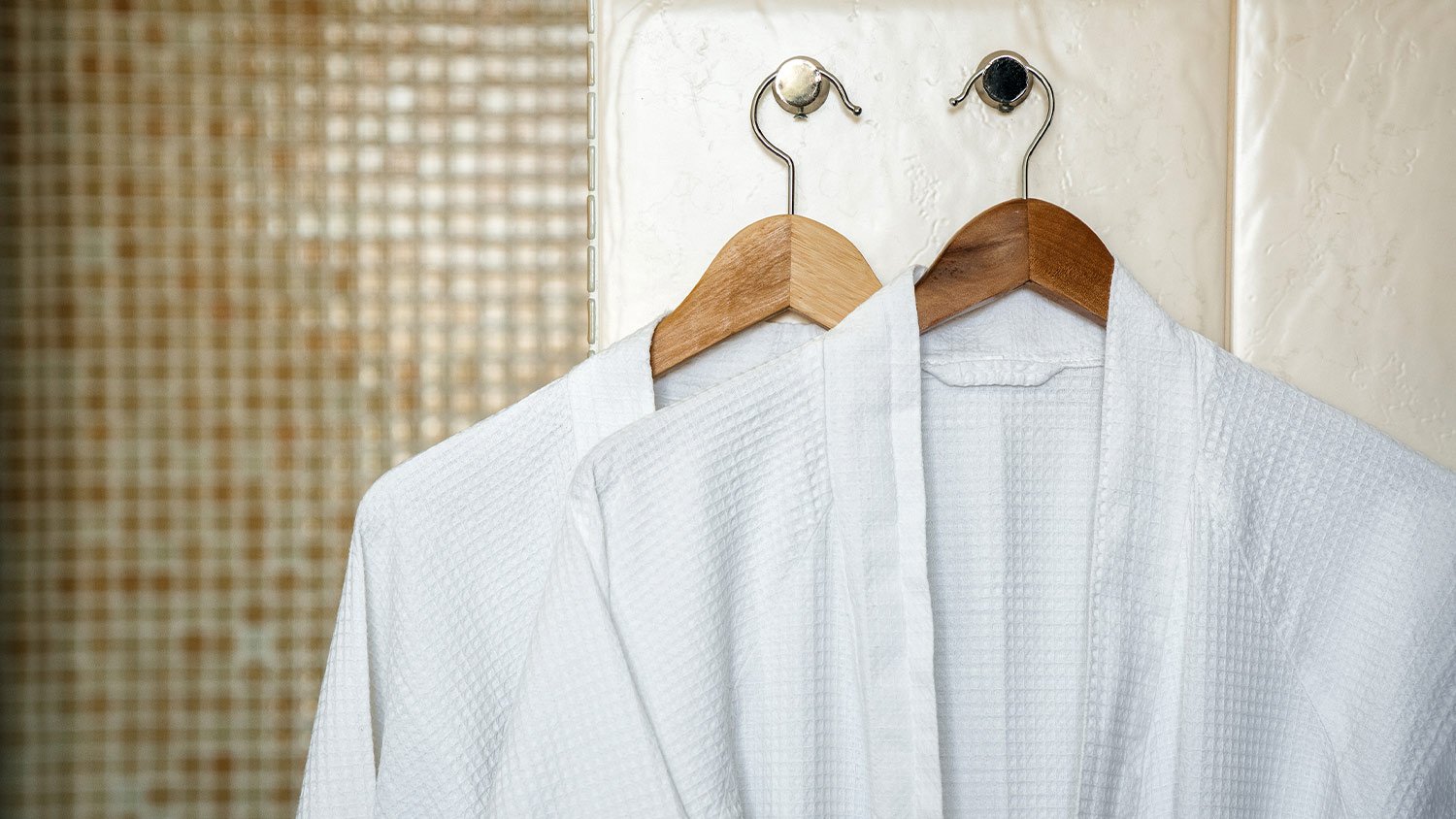 two white cotton robes hanging in bathroom