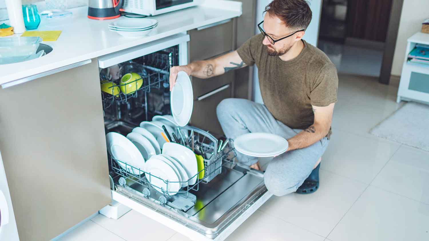 Man taking clean dishes out of the dishwasher 