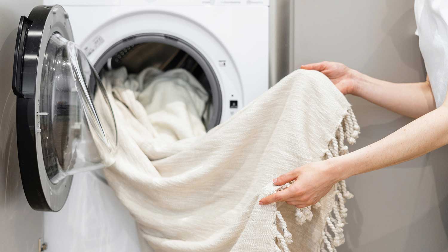 Woman taking linen out of the washing machine