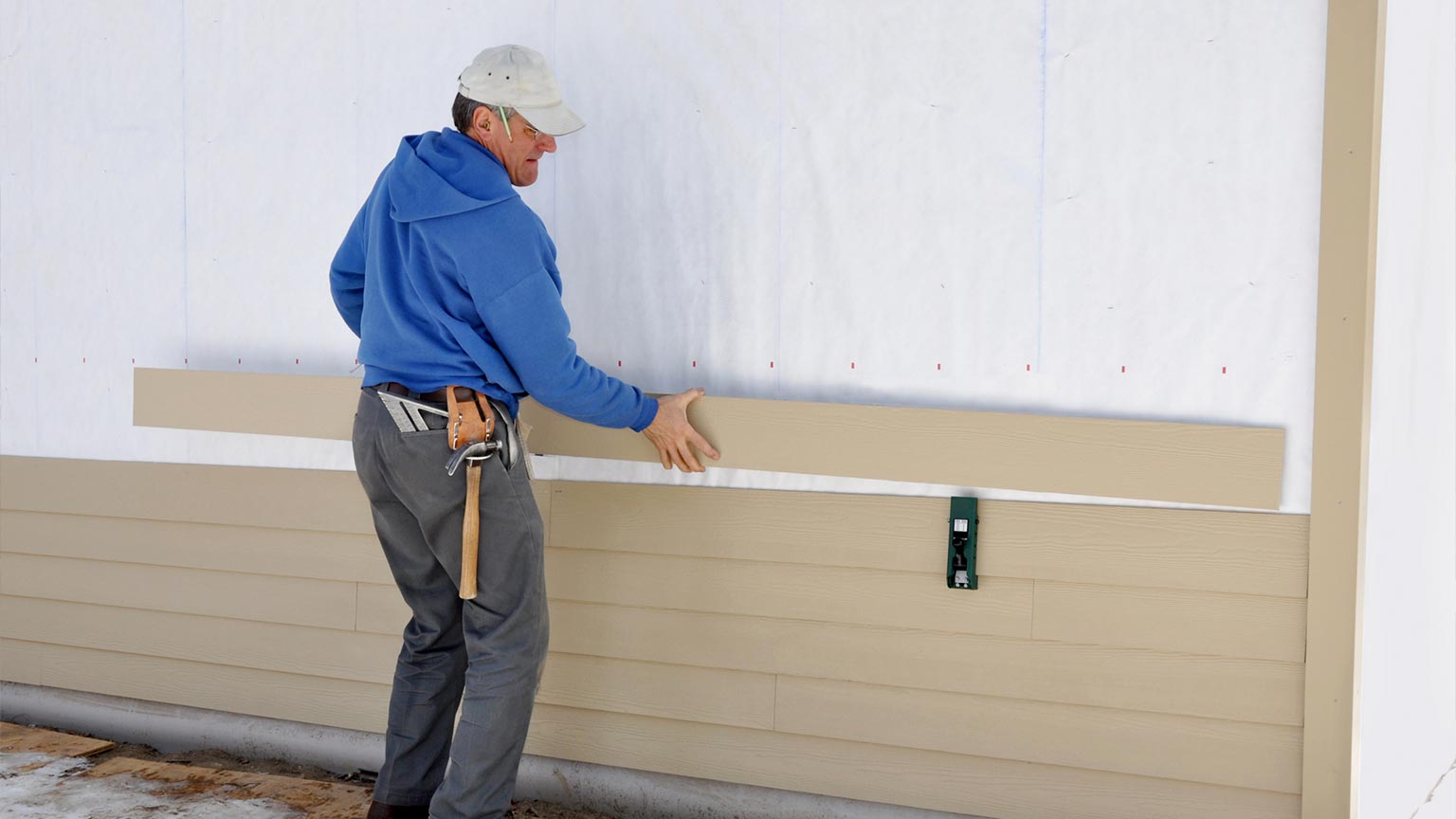 Carpenter using a gauge to install house siding