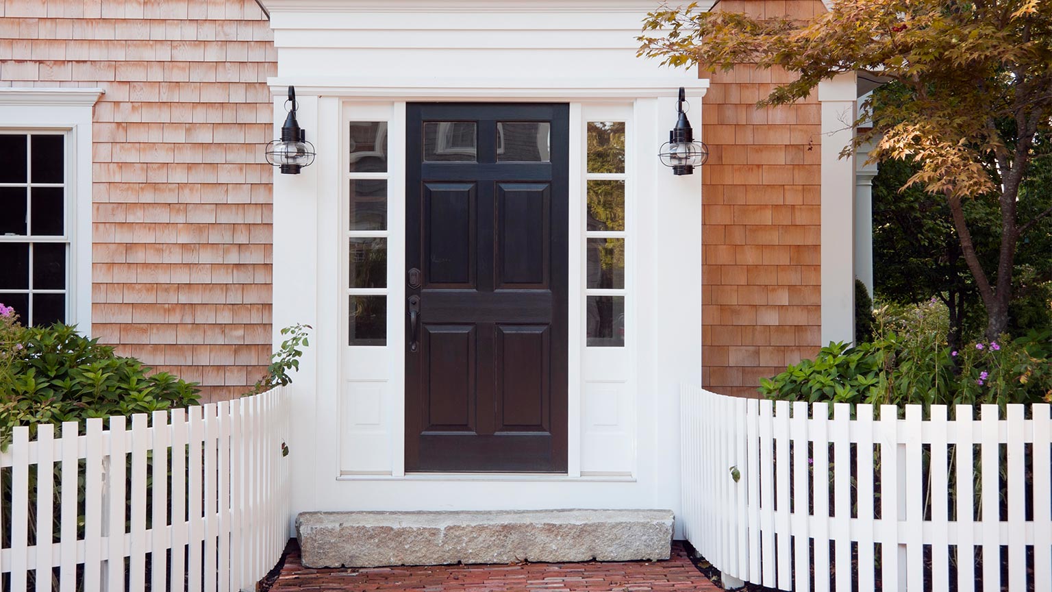 Entryway of brick New England home with picket fence