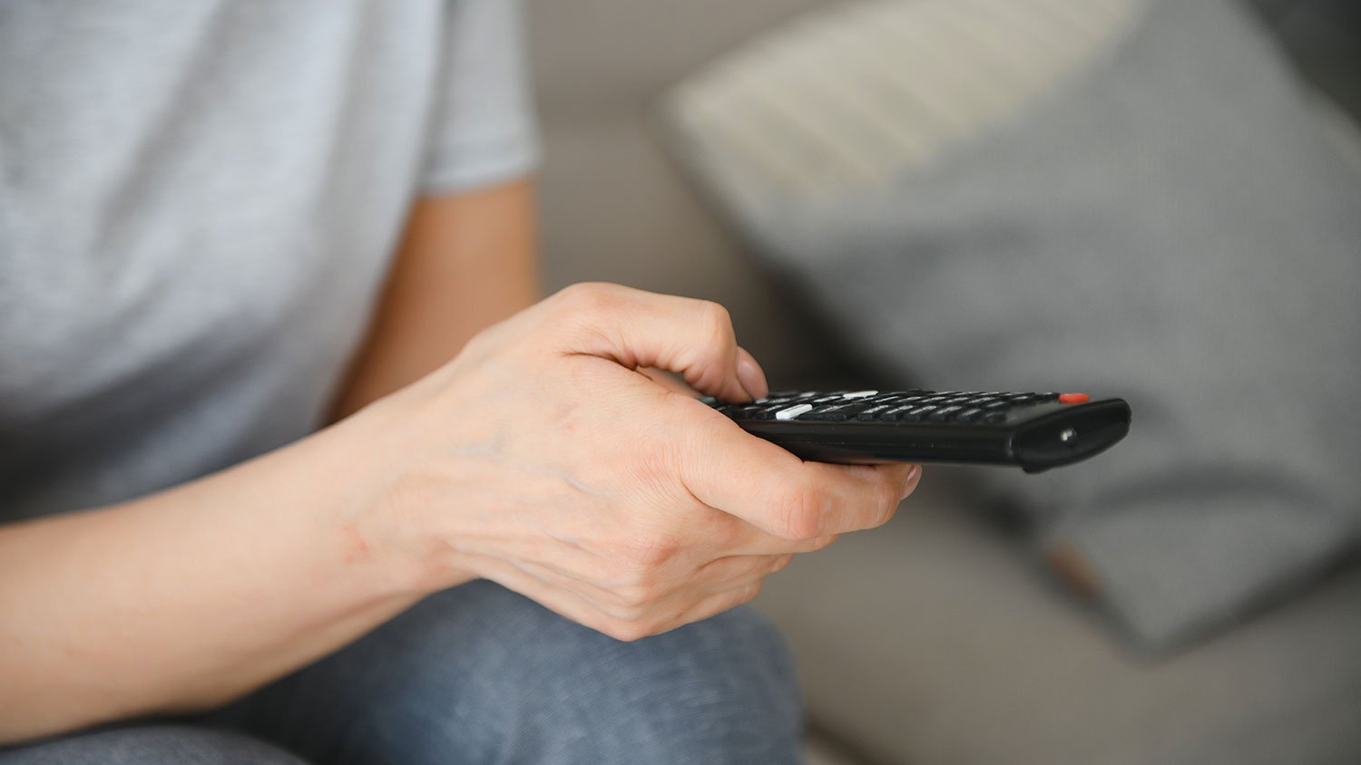 Closeup of a woman using remote tv remote control