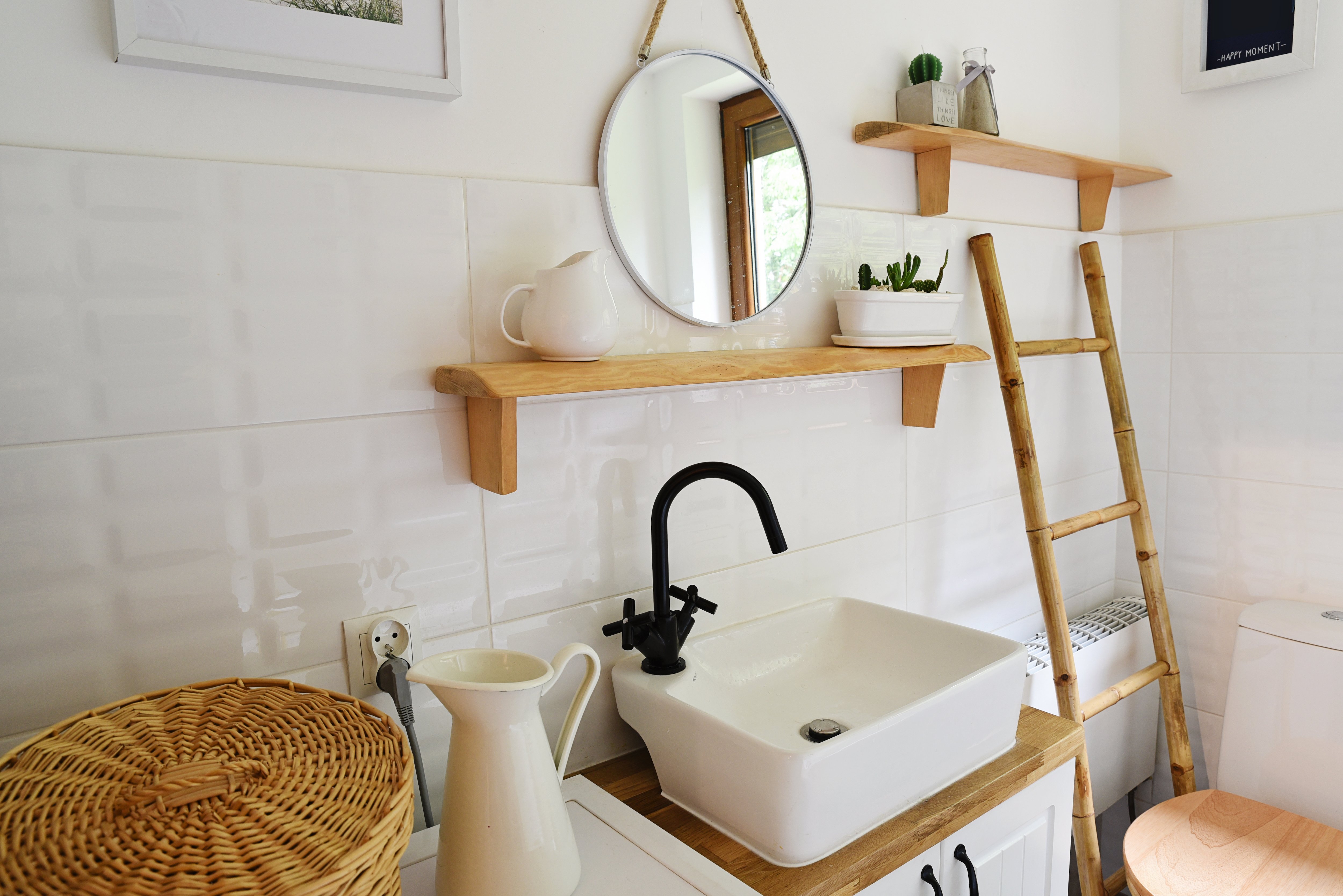 Bathroom with wooden ladder next to toilet, open wood shelves, small square sink, and white tile