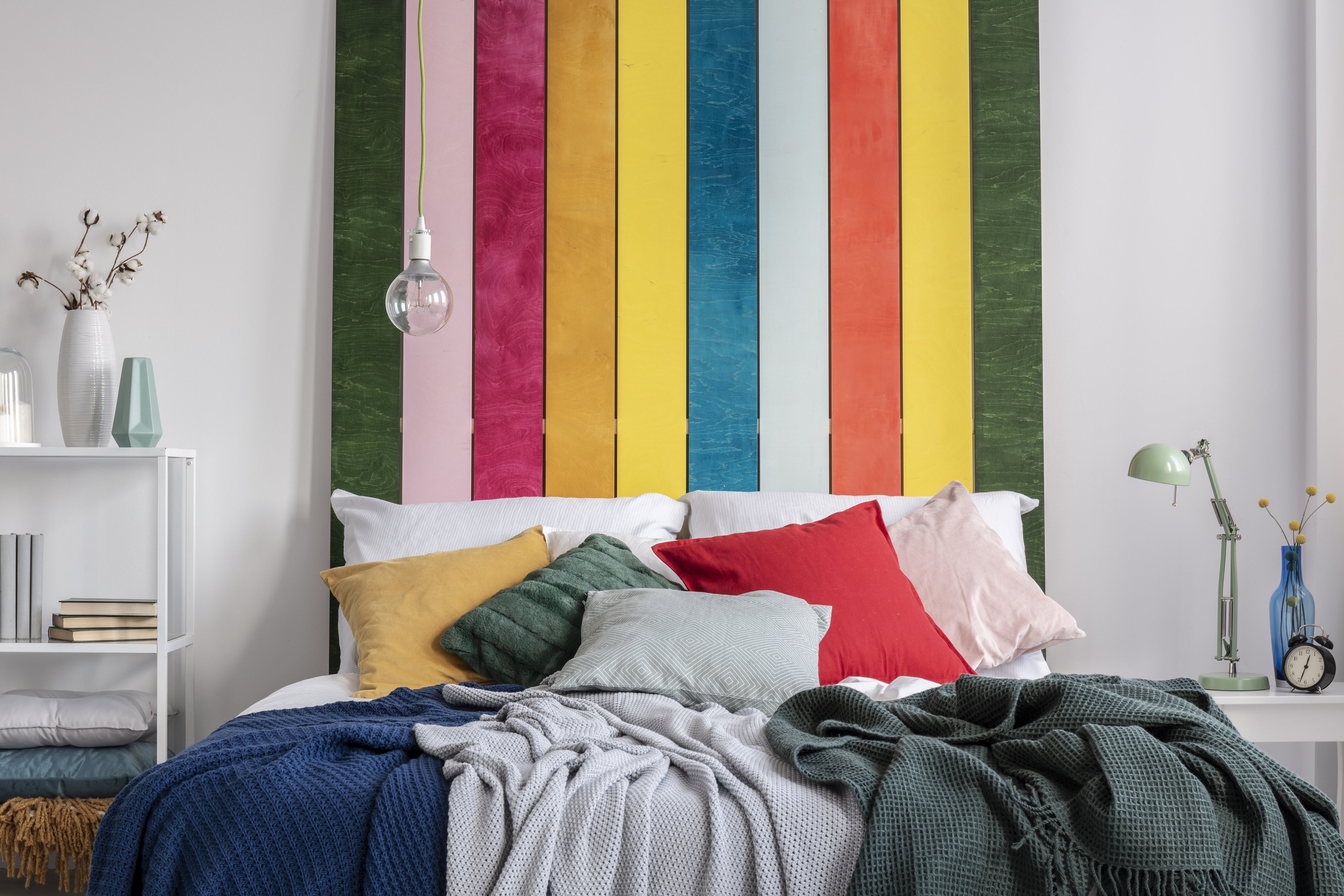 A small bedroom with bright rainbow colored vertical stripes