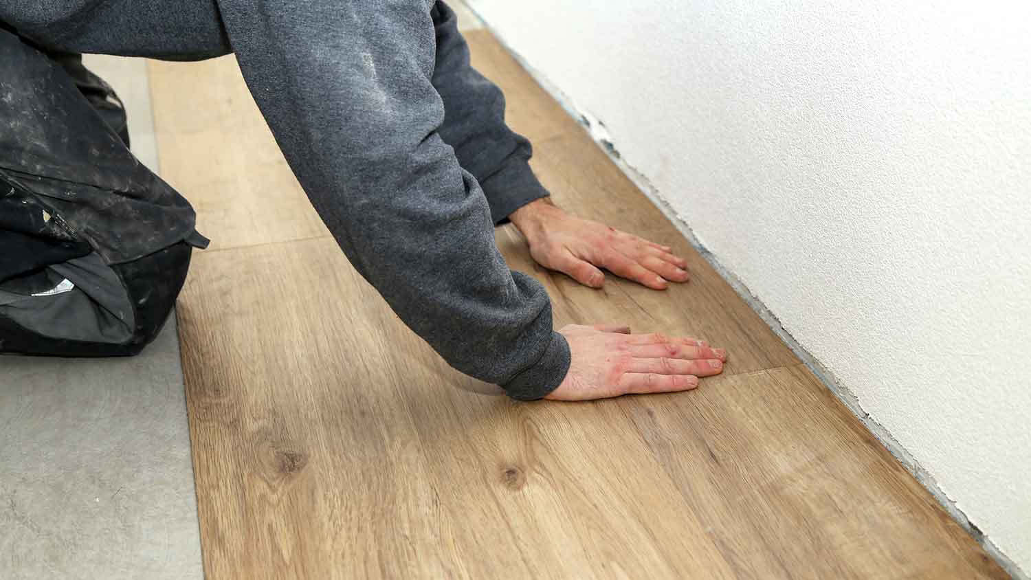 Worker installing vinyl flooring in the room 