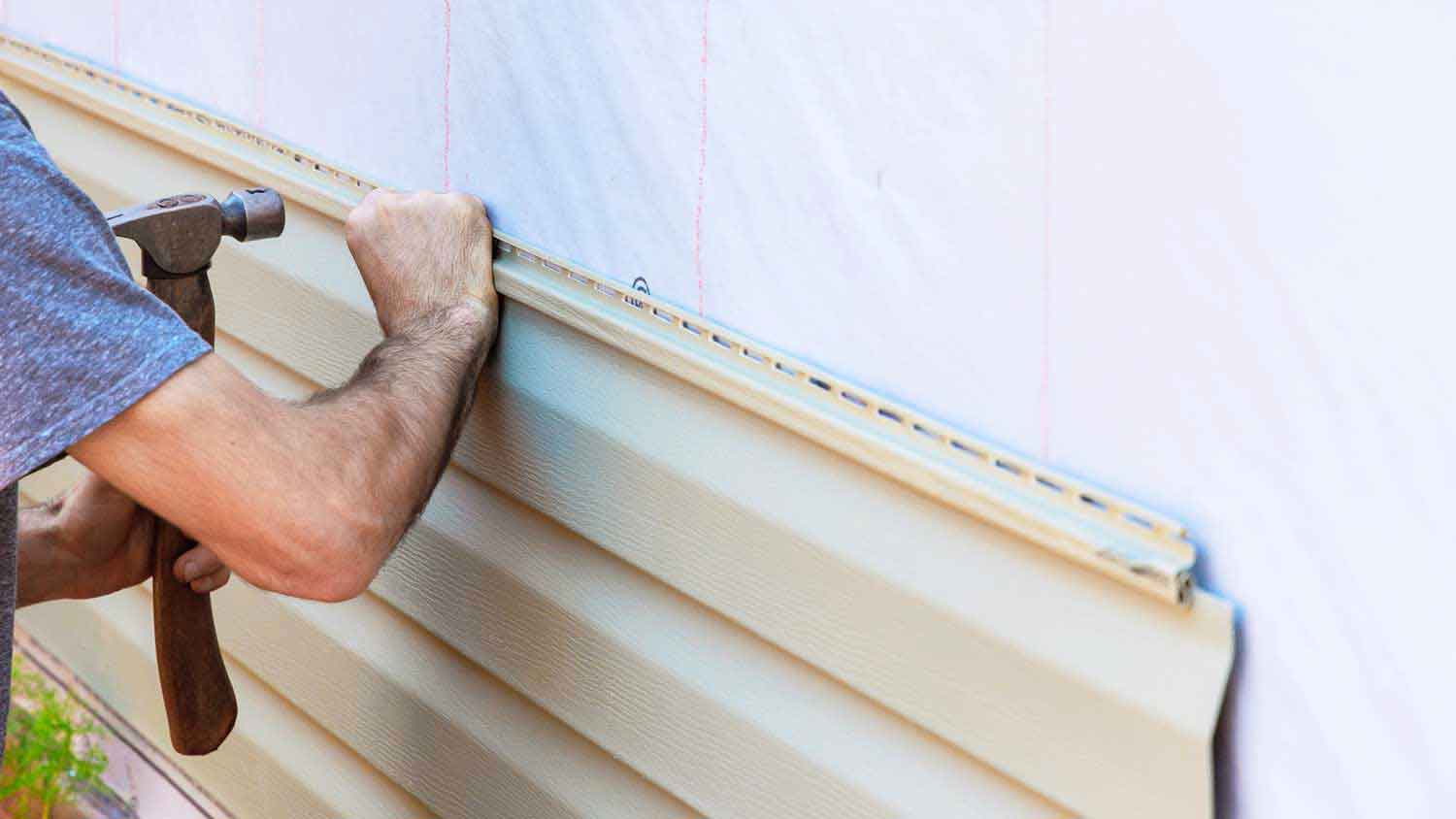 Worker installing new vinyl siding on the house