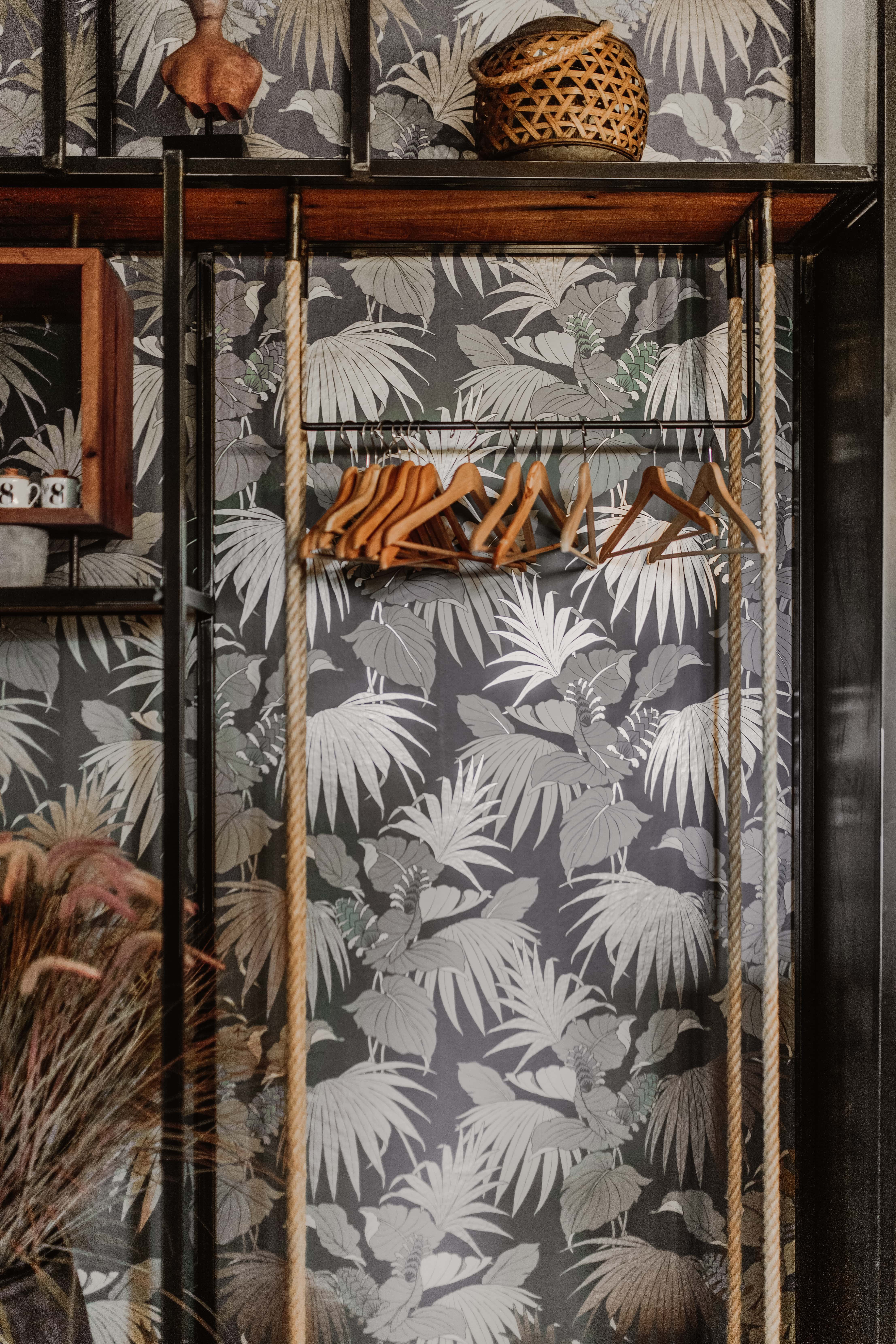 A closet organizer in front of a wallpapered accent wall