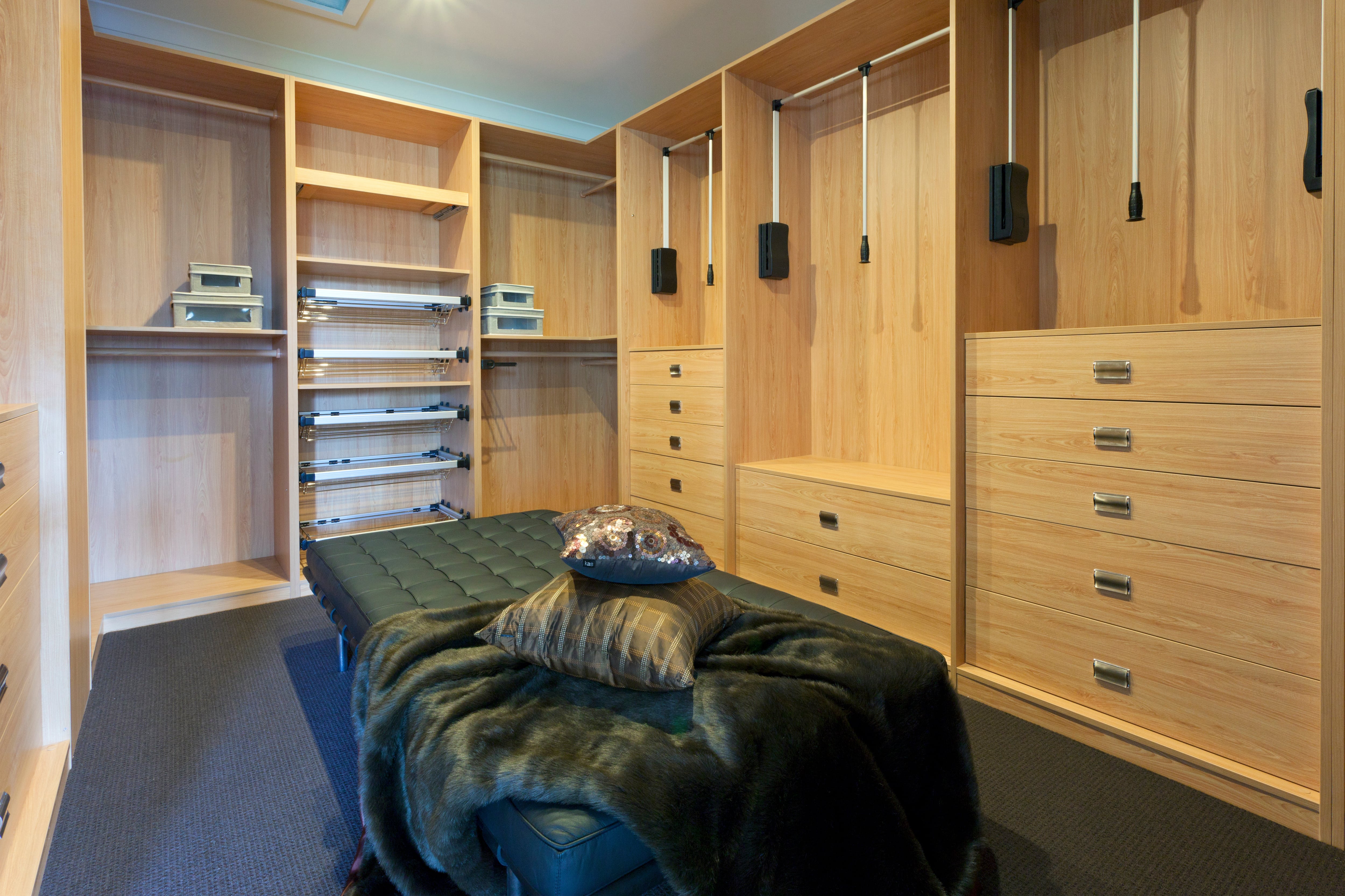 A walk-in closet with a large black leather ottoman in the middle