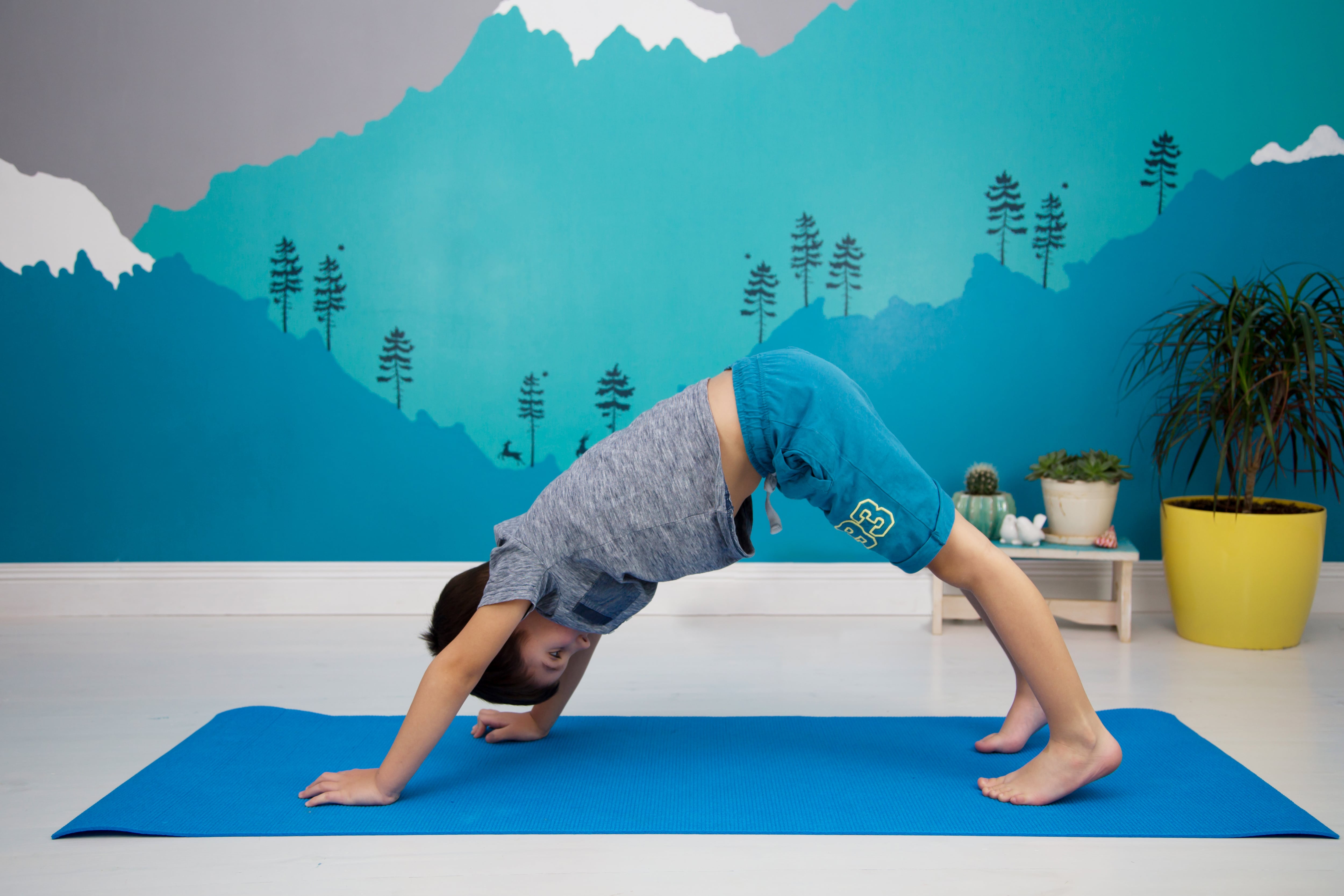 Little boy doing yoga in room with mural on wall