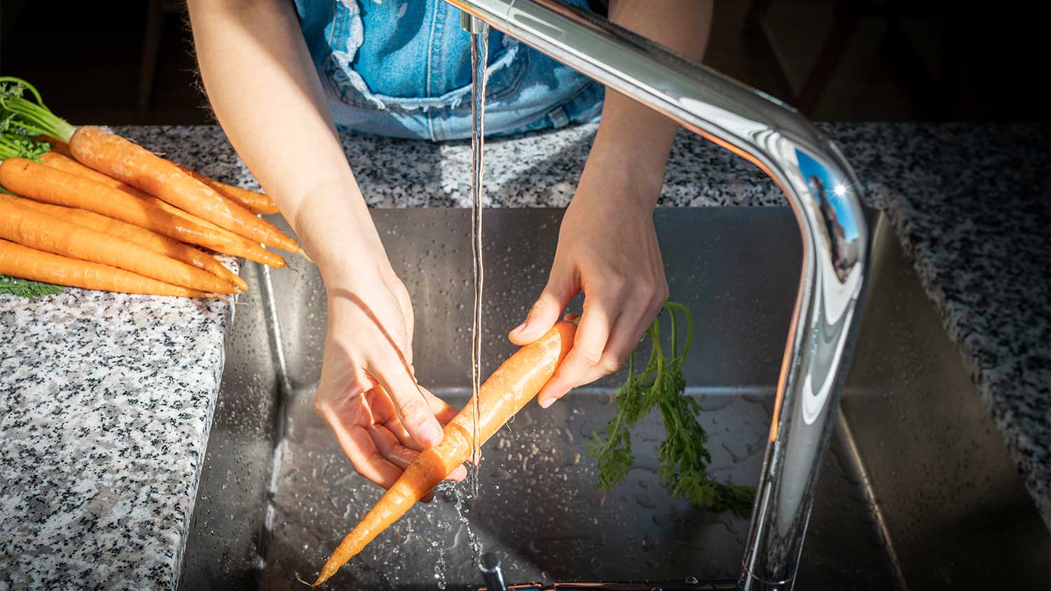 Washing carrots in stainless steel kitchen sink