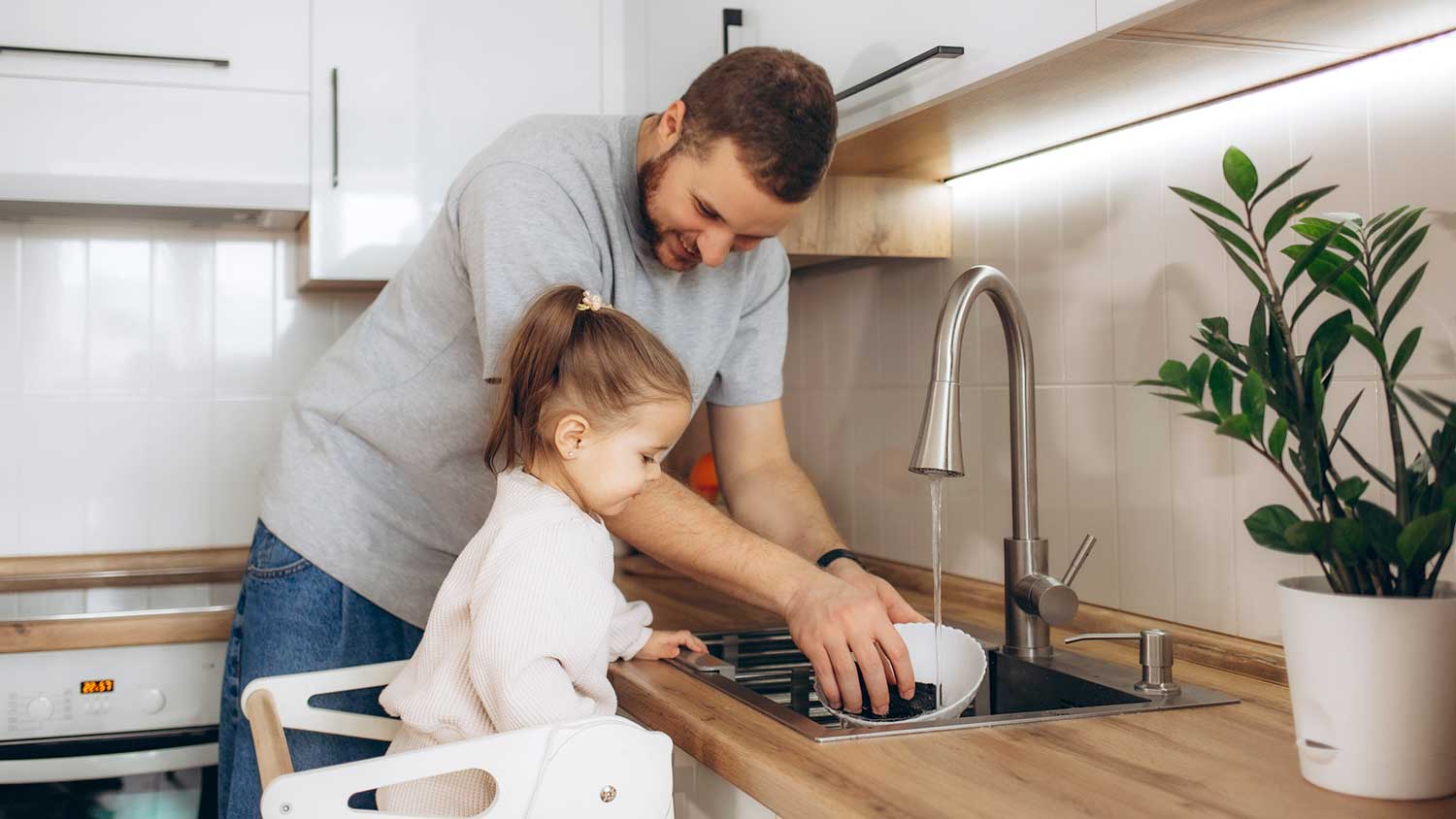 Little girl helping dad wash the dishes 