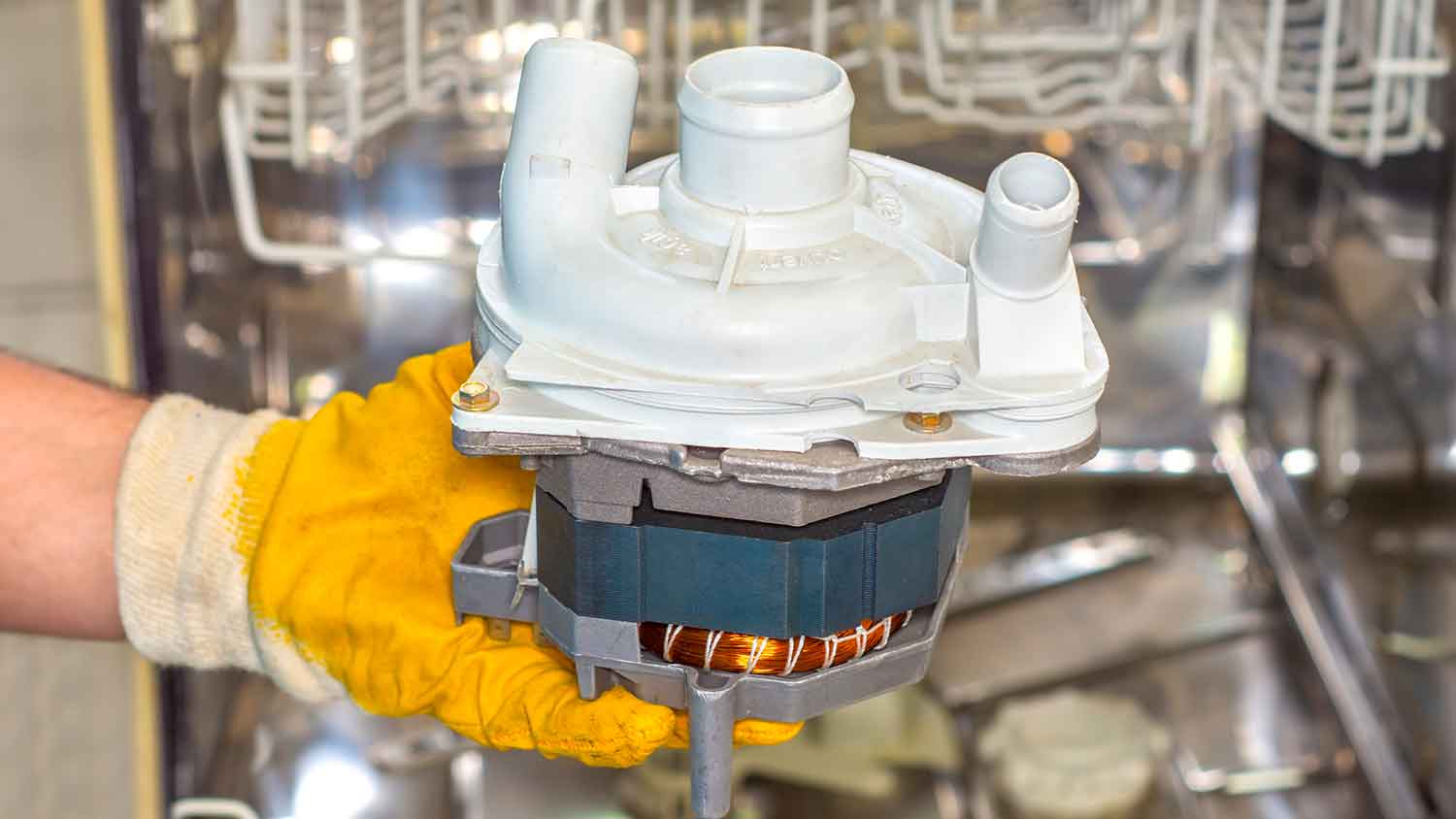 A person wearing gloves holding a dishwasher circulation pump