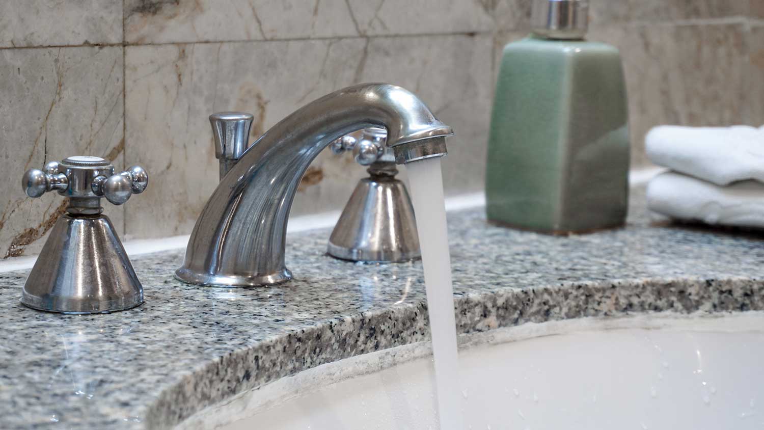 Water running from a stainless-steel bathroom faucet