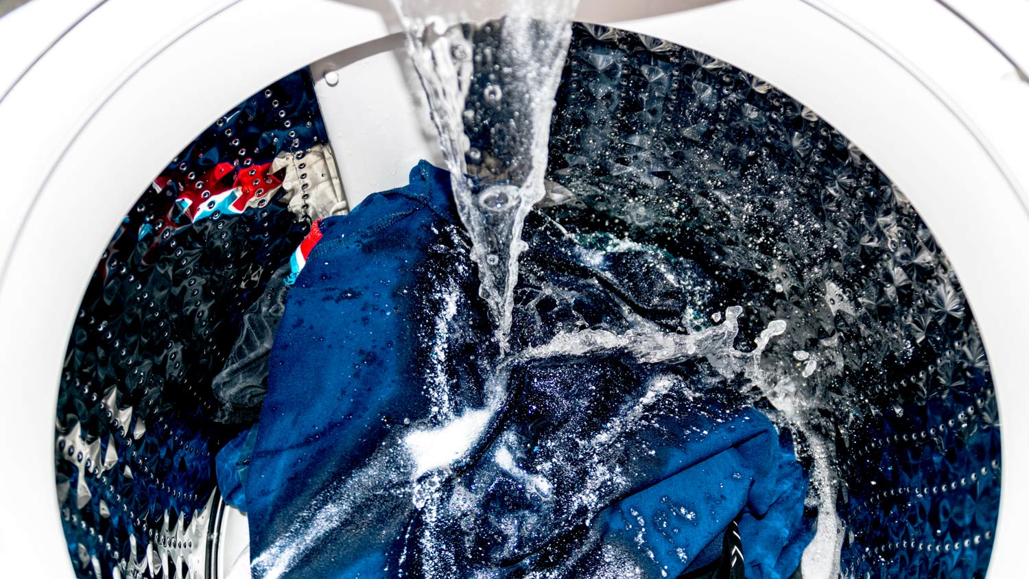 Close-up of washing machine running full cycle soapy water 