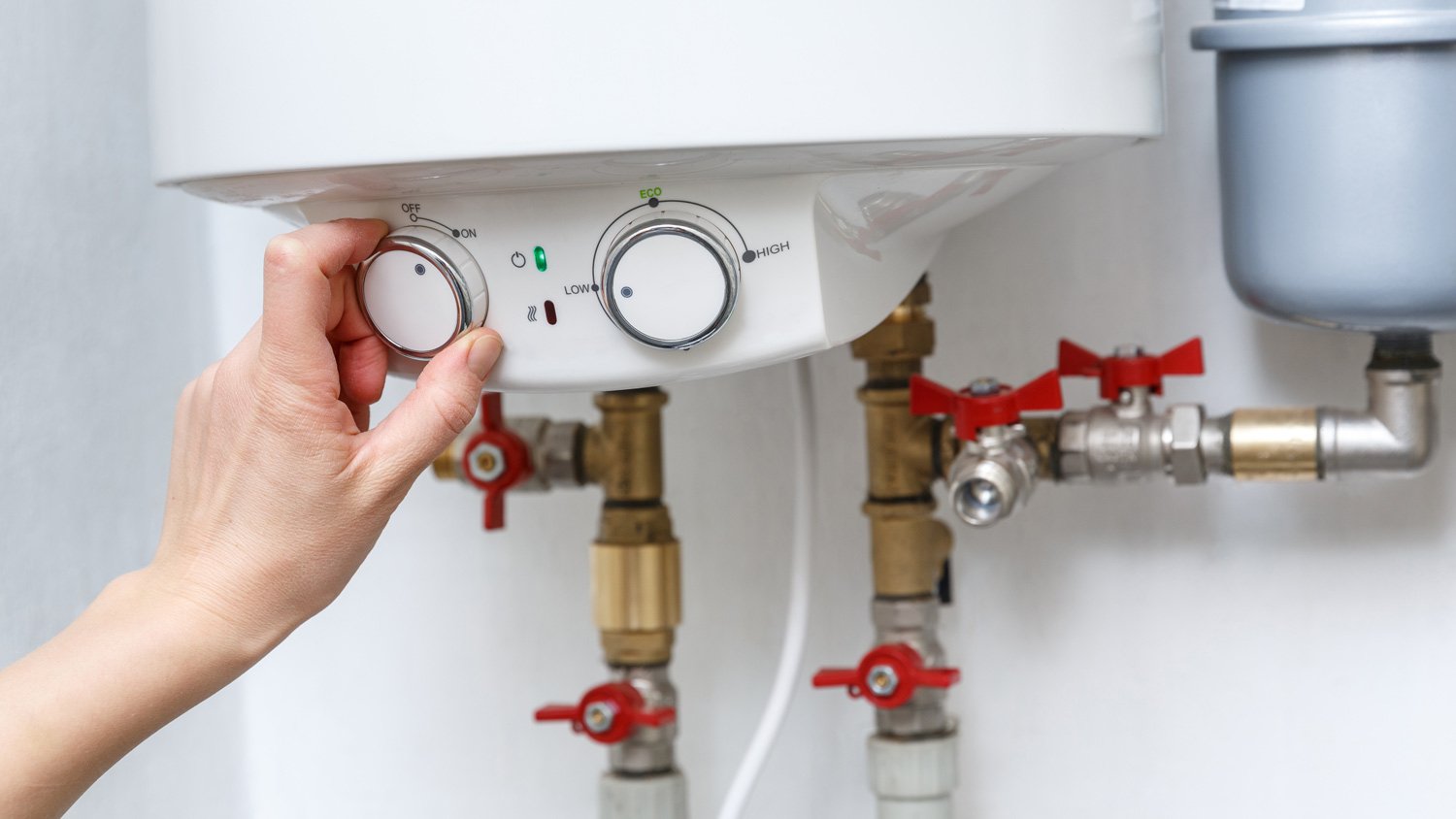 Female hand turning on electric water heater  