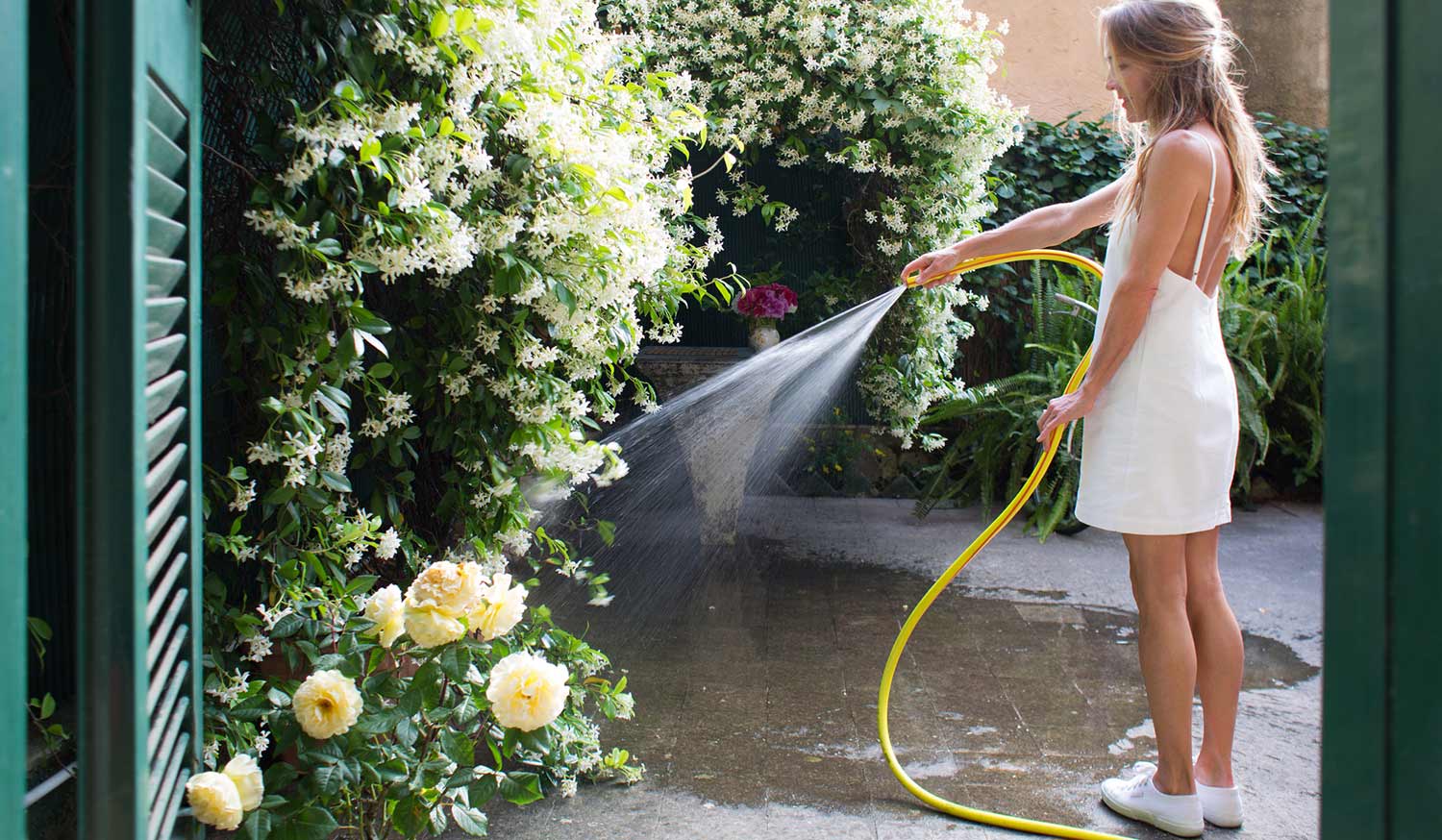 Woman watering flowers in her backyard