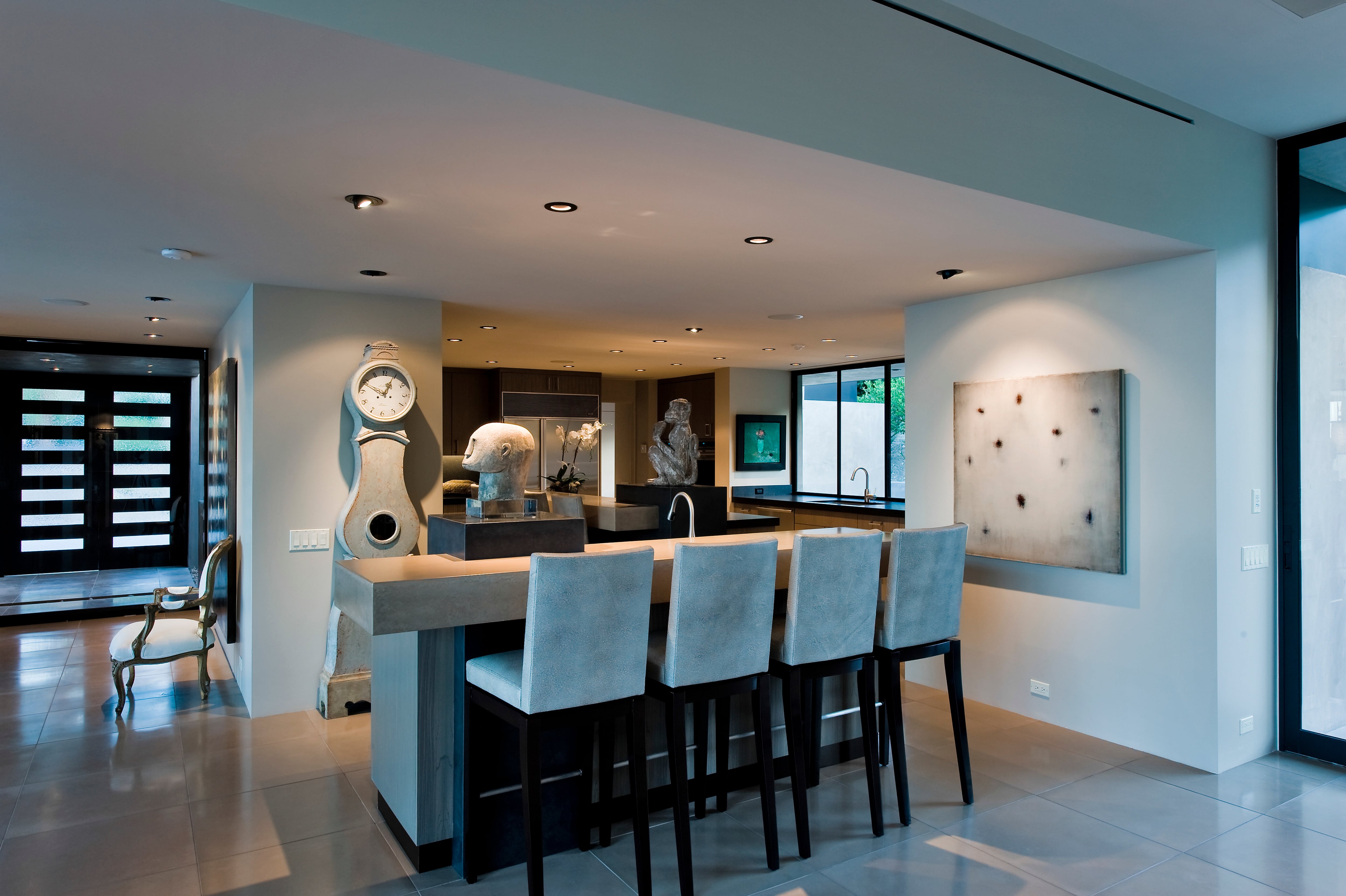 A wet bar with stone sculptures, countertops, and a modern painting