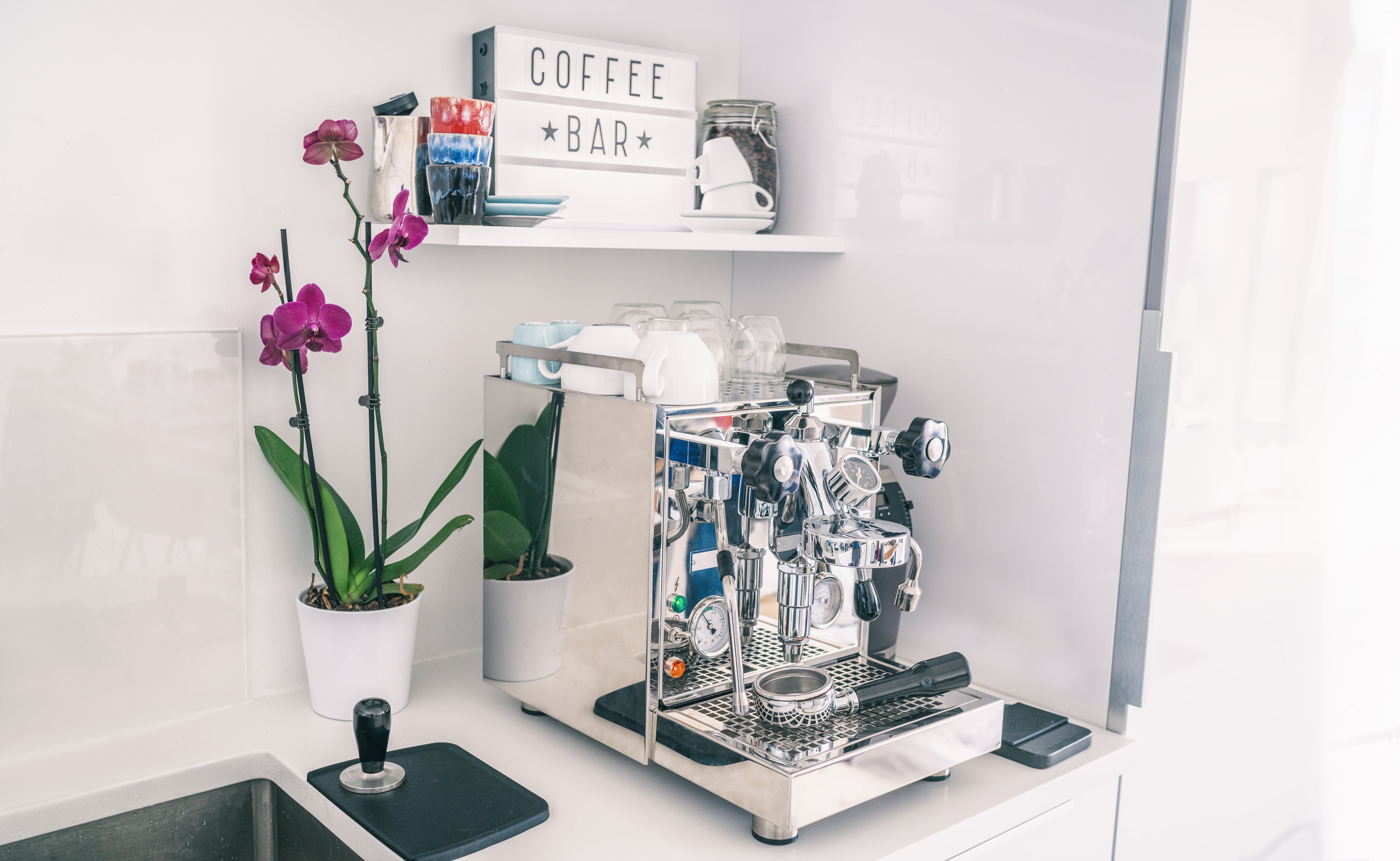 A home coffee bar with espresso machine and an orchid