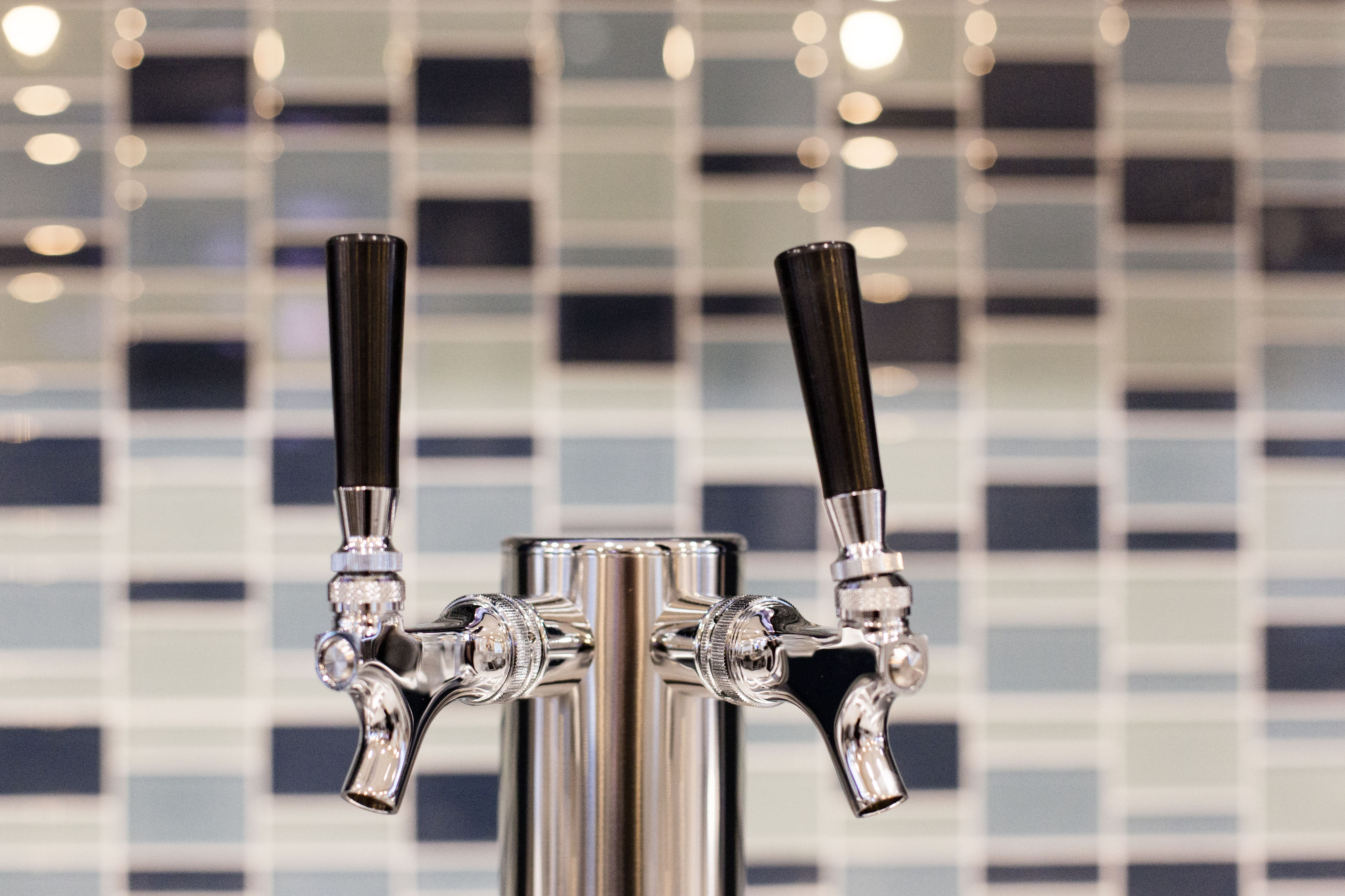 A beer tap against a mosaic tile backsplash