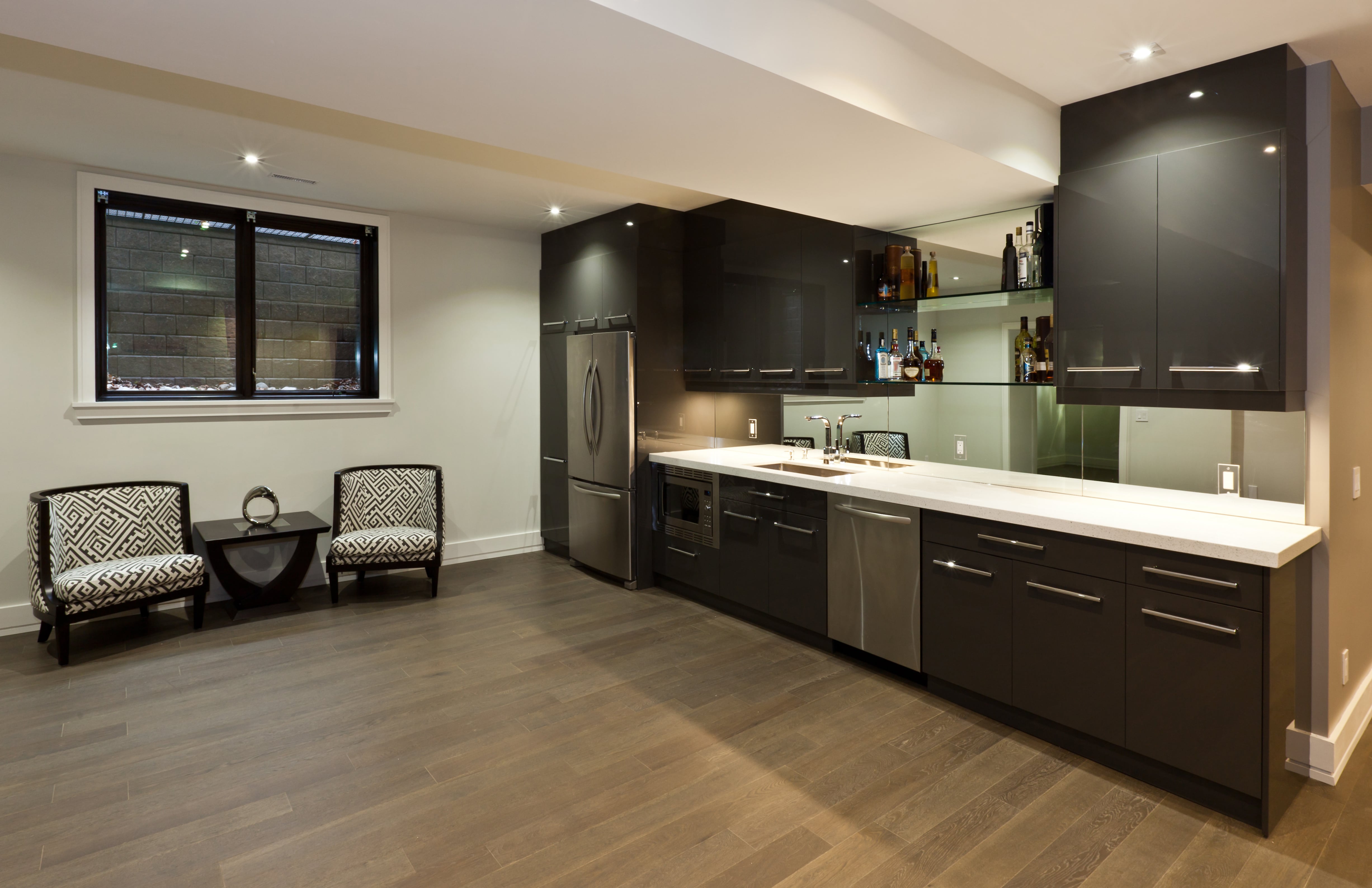 An entertainment room with a wet bar, black overhead cabinets, and open shelving