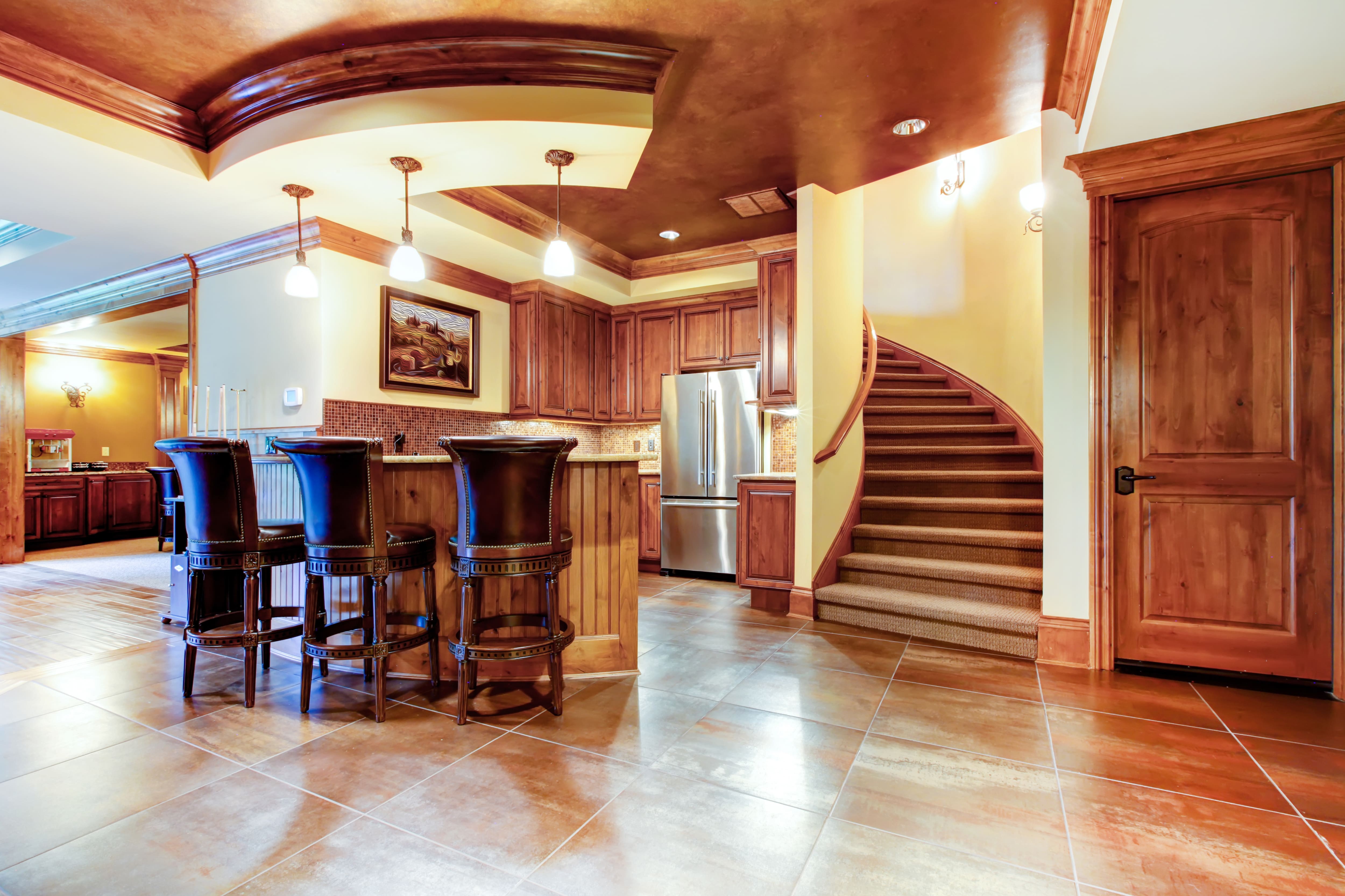 A basement remodel with a circular wet bar in dark wood and terracotta