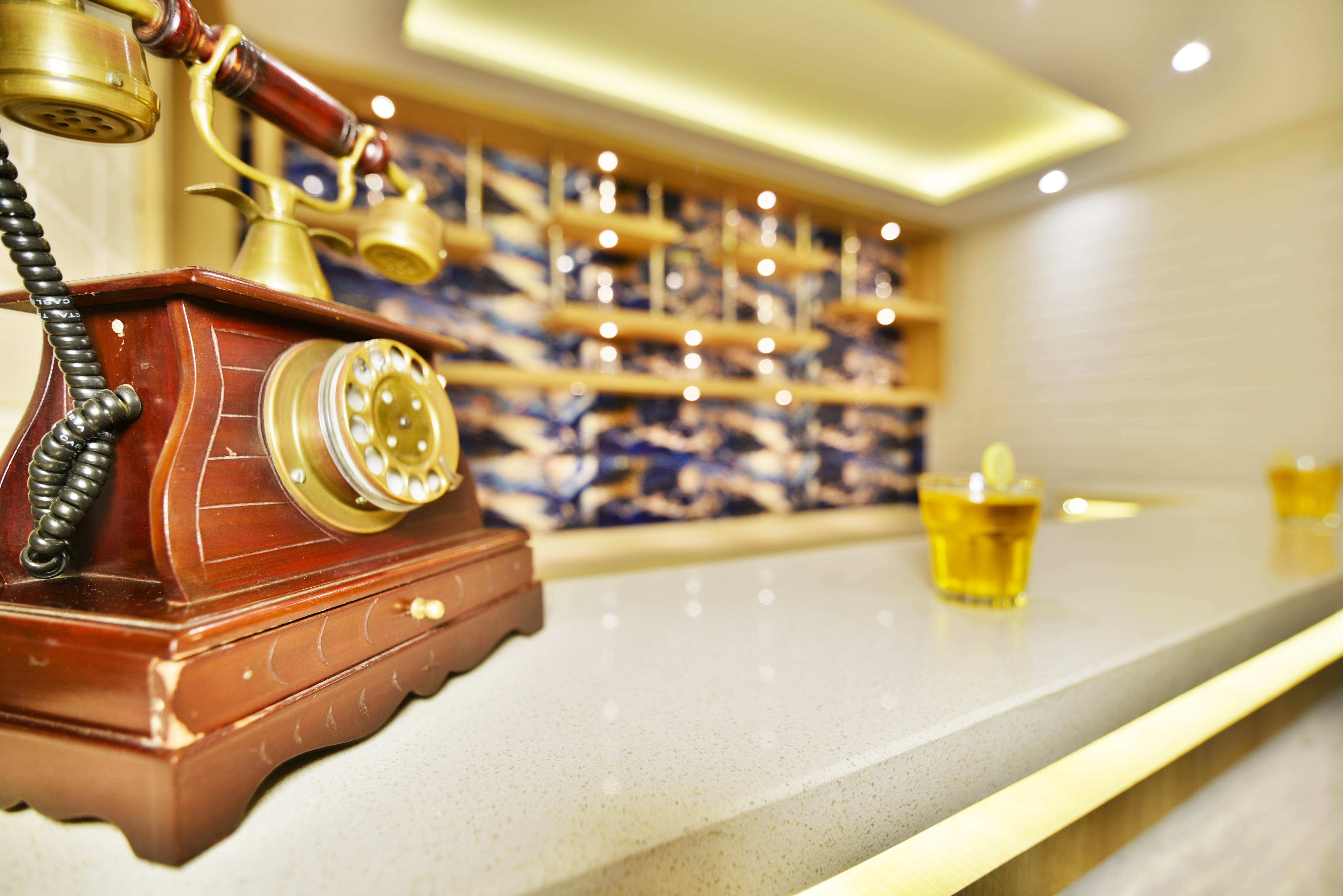 A home bar with a vintage telephone, liquor shelves, and cocktails 