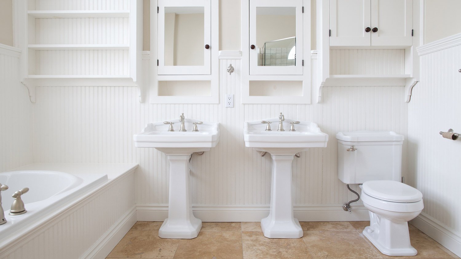 A white bathroom with a bathtub and two sinks