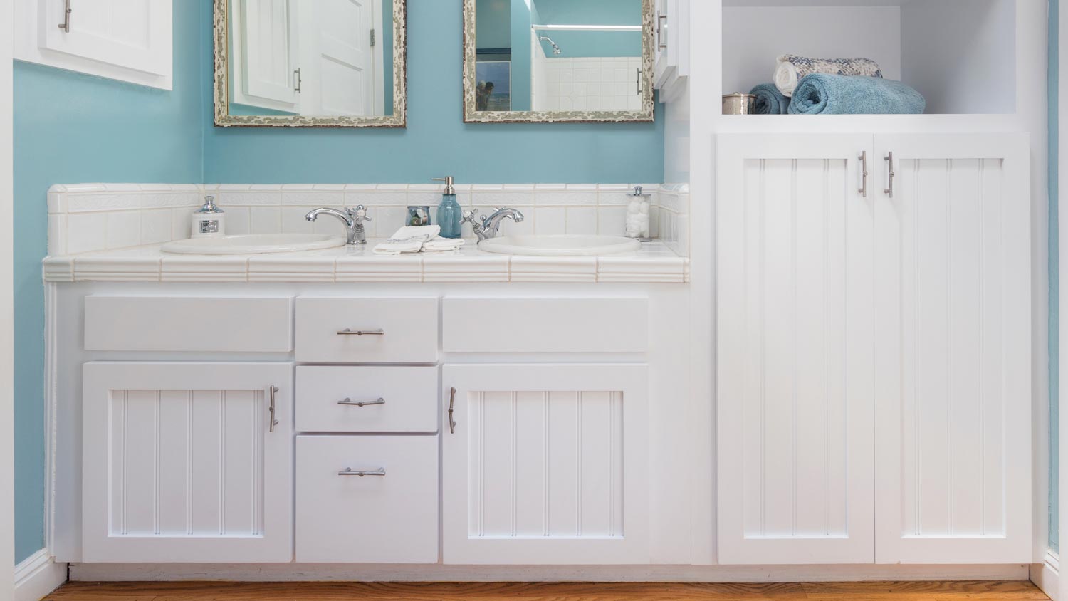 A bathroom with white cabinets and blue walls