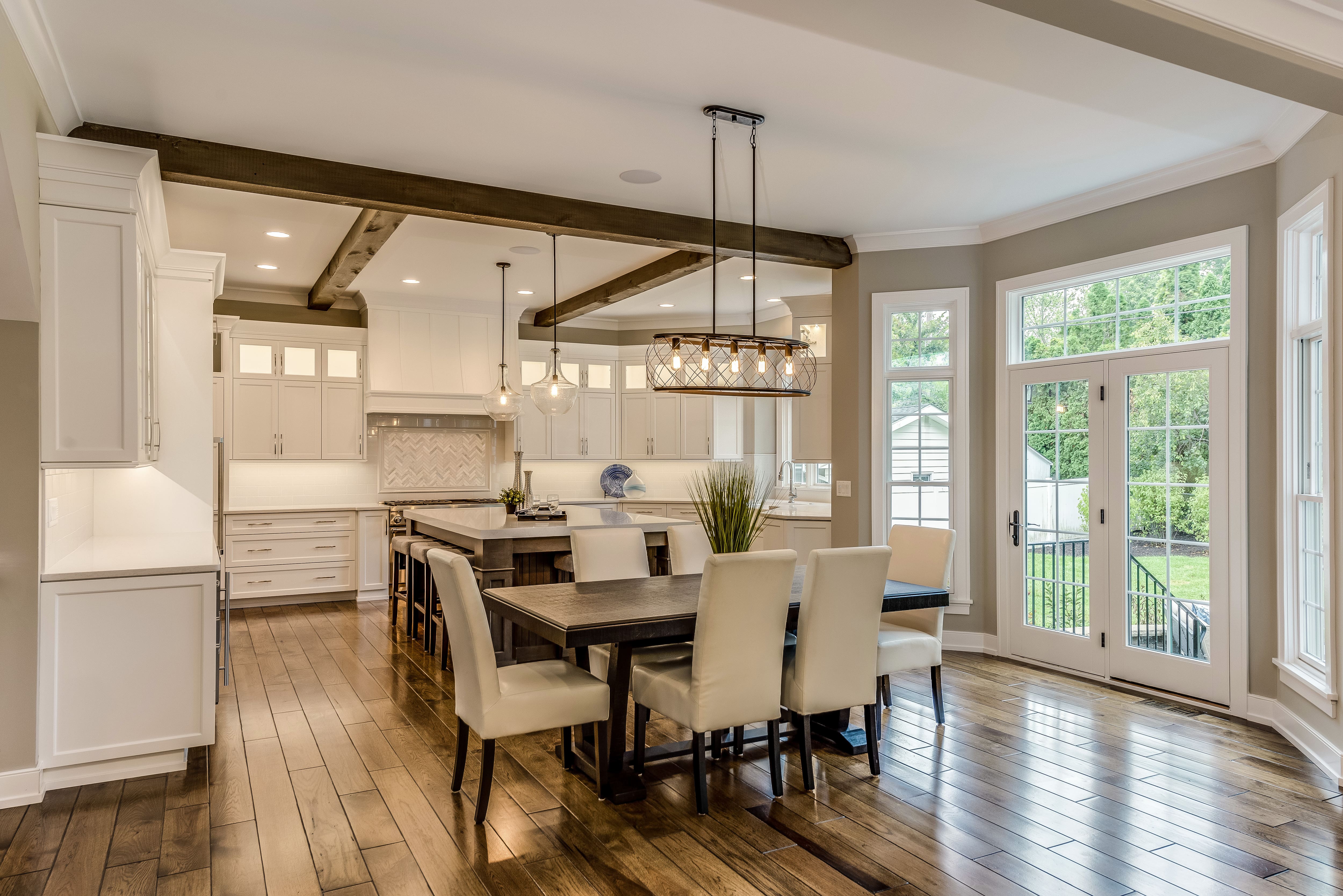 A spacious white kitchen with wooden furniture, accents, and ceiling beams