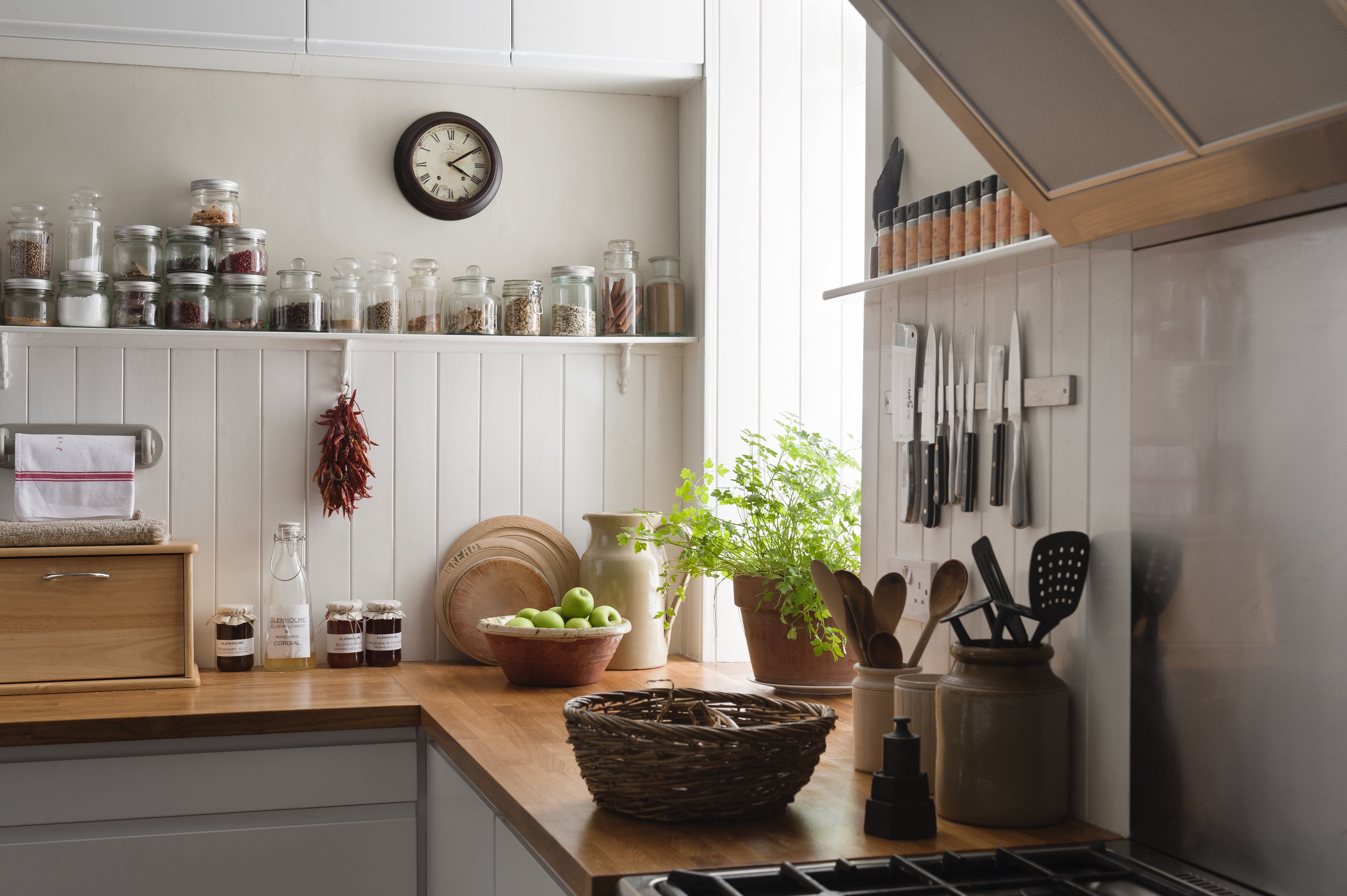 A cozy white kitchen with open shelving holding colorful glass jars