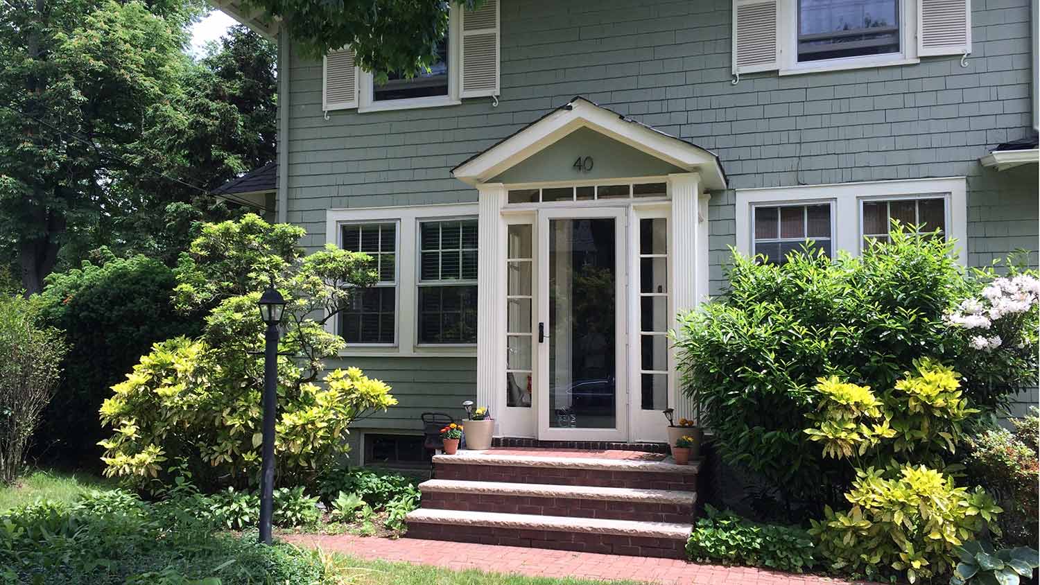 White storm door on green two-story house