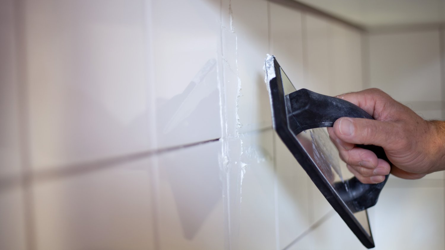 Applying white grout in kitchen