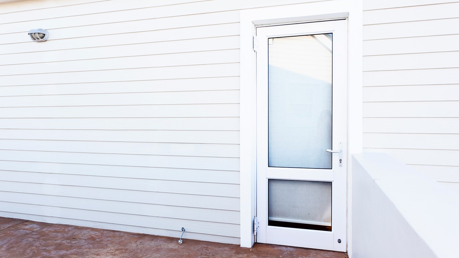 Outside wall and glass door of white painted clapboard house