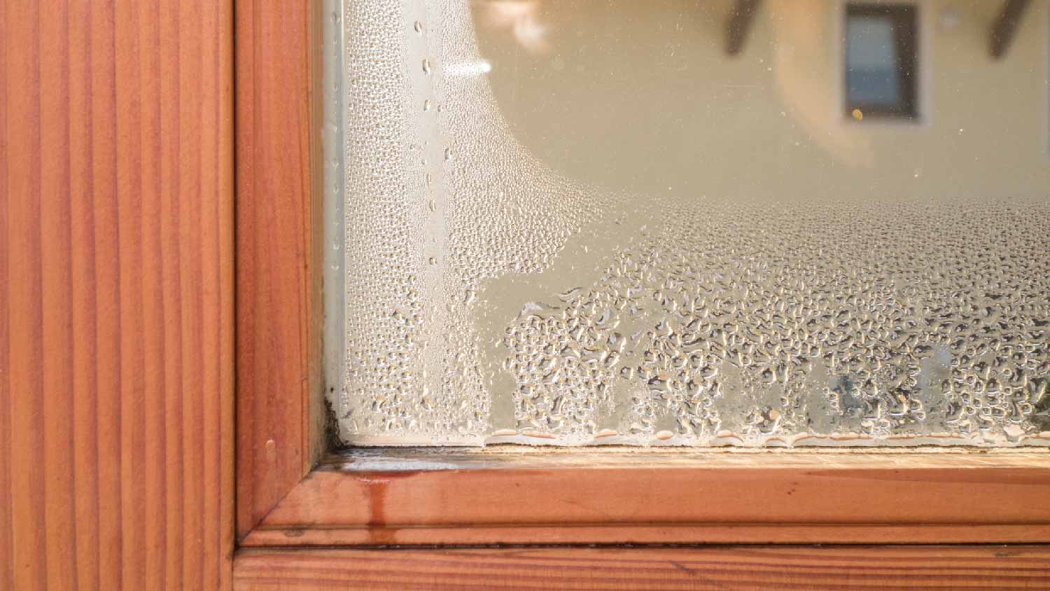 A wooden window frame is dripping water