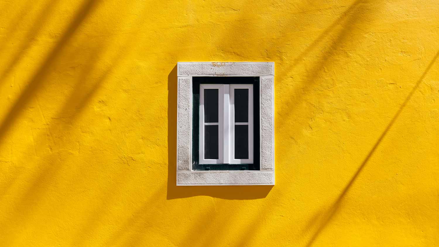A window of a vibrant mustard yellow house