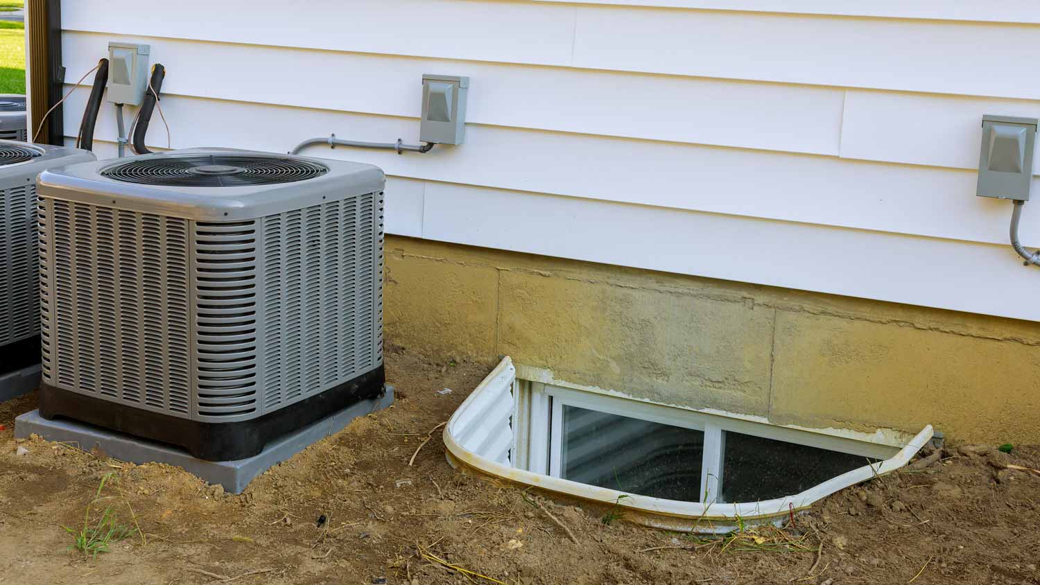 A window well next to a HVAC in a backyard