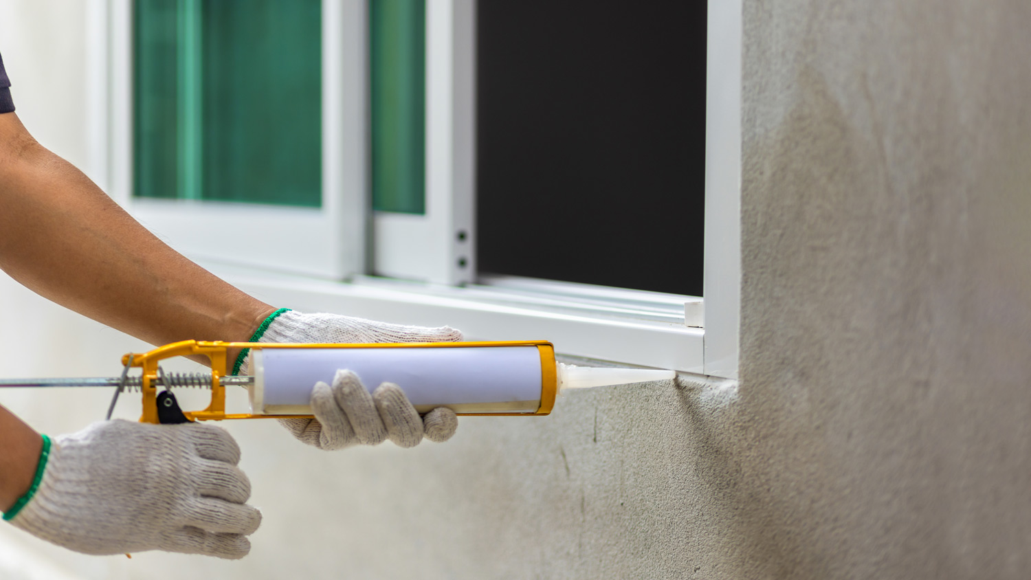 Construction worker using silicone sealant caulk the outside window frame